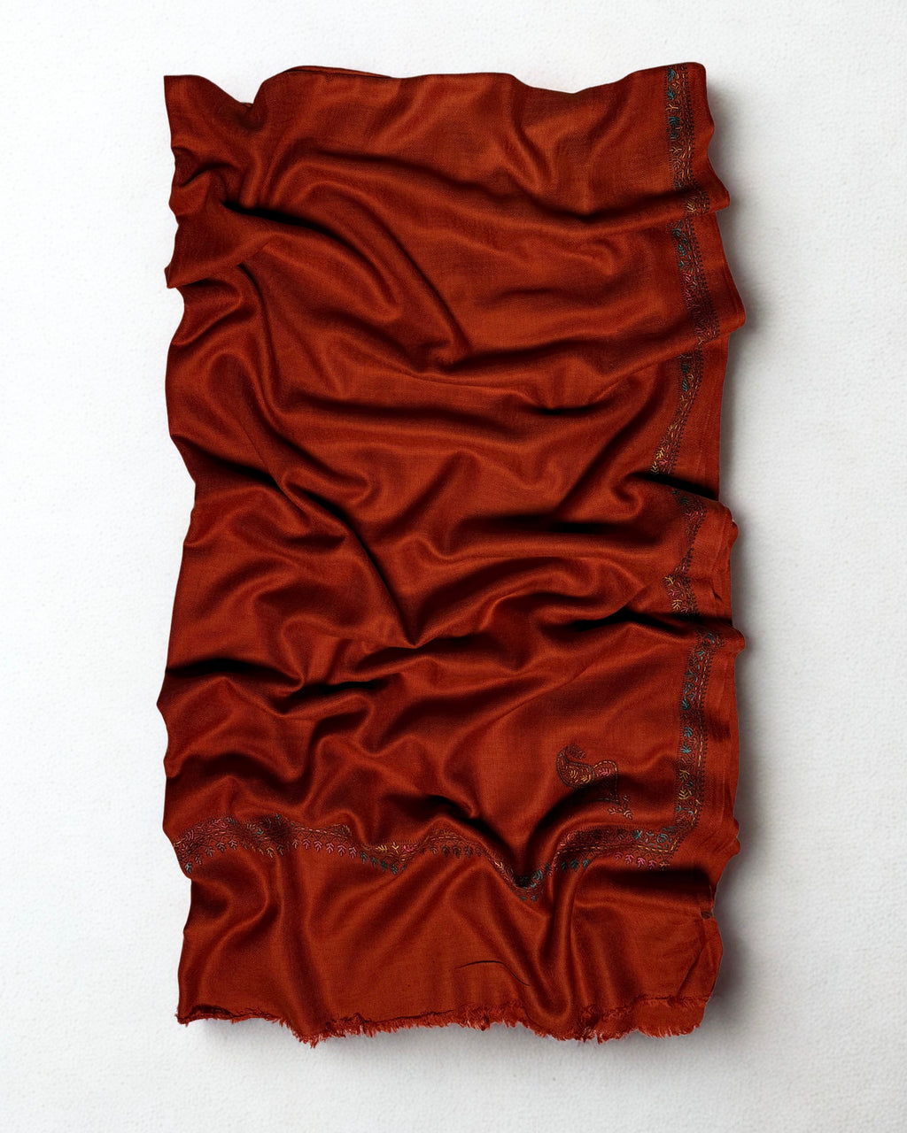 Close view of the teal, rose and ochre hand embroidery on the border of a rust Swati Shahtoosh shawl