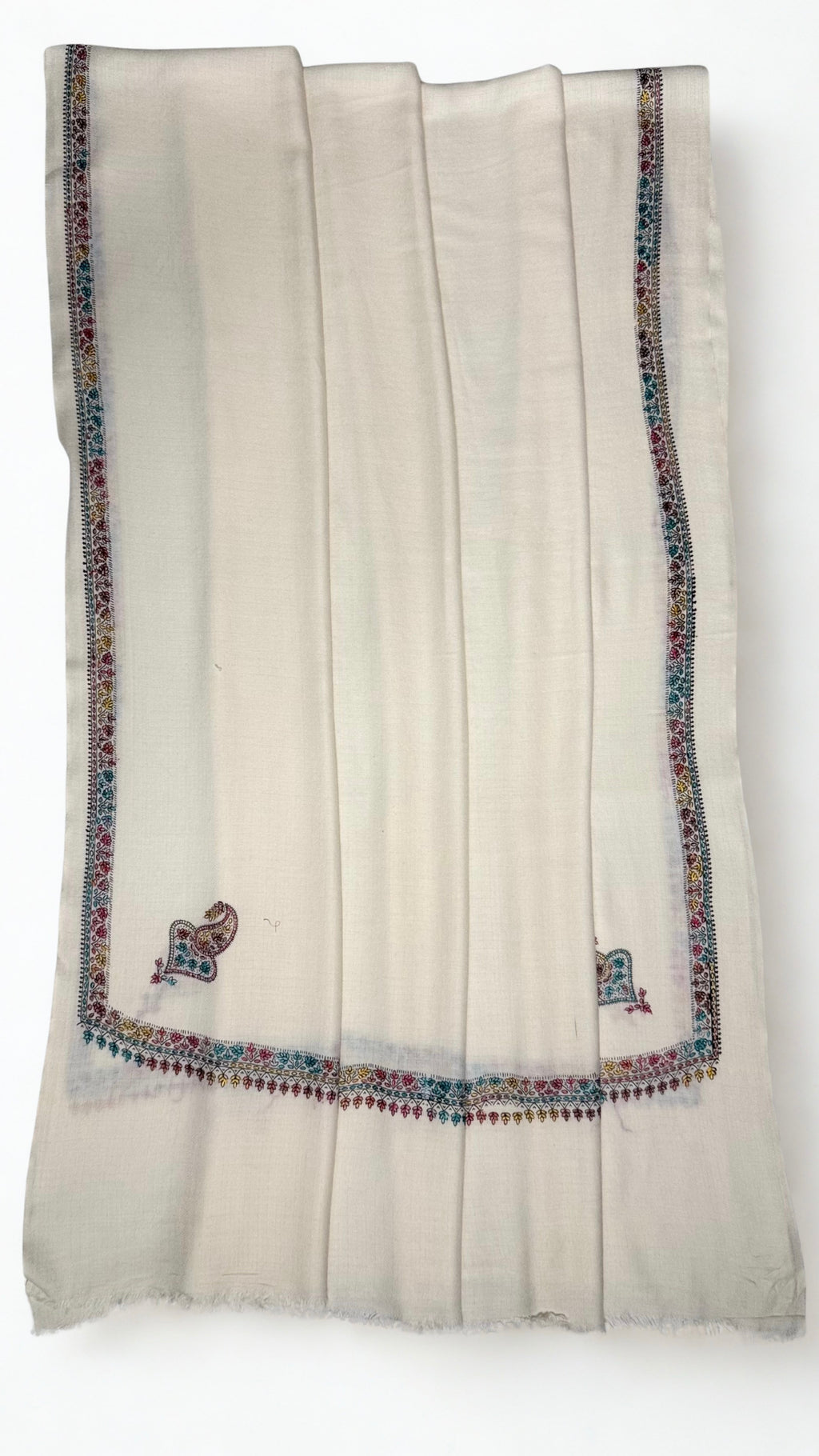 White Swati Shahtoosh shawl folded back to show the corner buta and embroidered border meeting at the corner