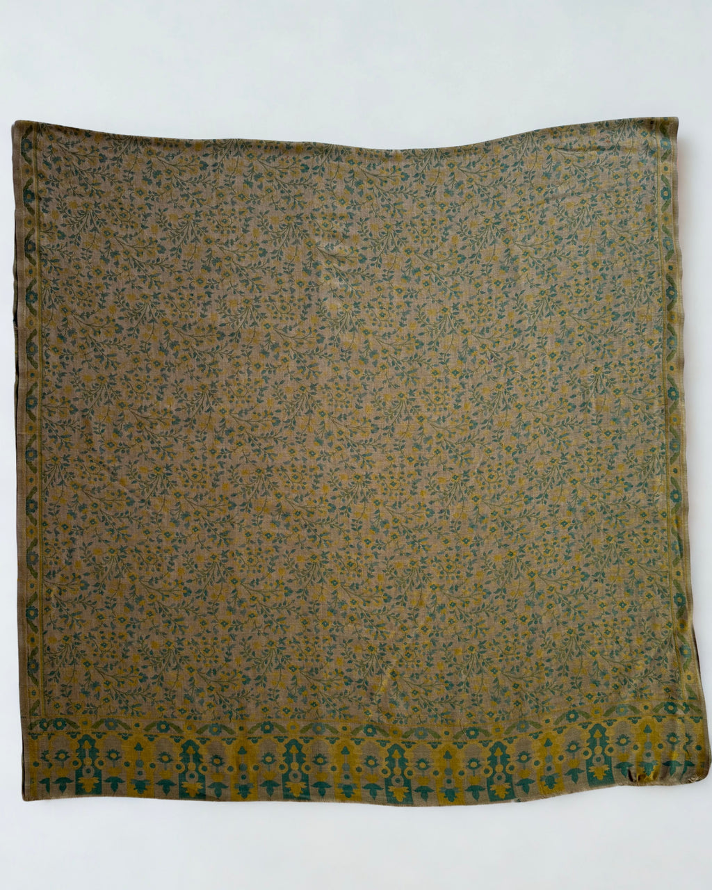 Detail of the bold teal and gold arched blossom end panel on a moss green Kani pashmina shawl
