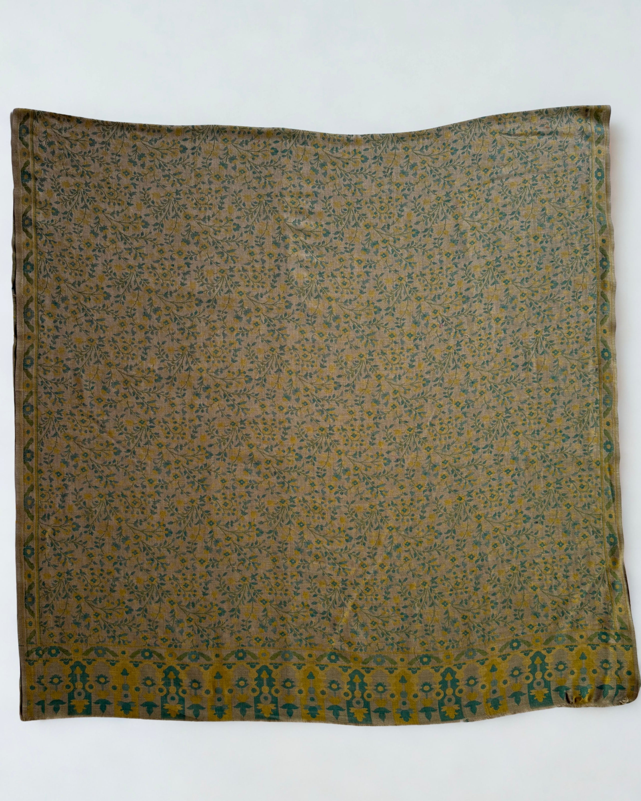 Detail of the bold teal and gold arched blossom end panel on a moss green Kani pashmina shawl