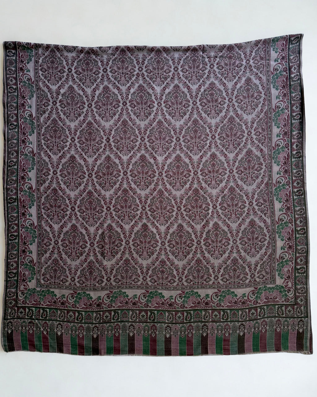 Close view of the ogee medallion lattice and arcaded striped end panel on a plum and moss Kani pashmina shawl