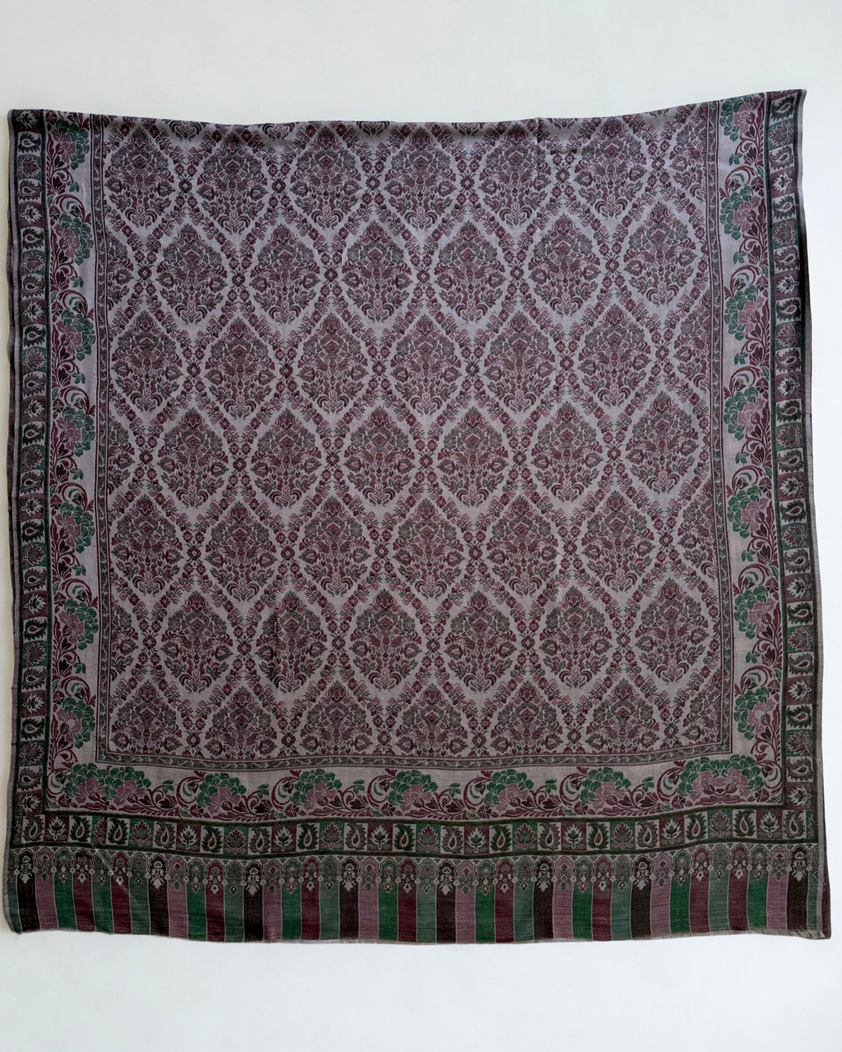 Close view of the ogee medallion lattice and arcaded striped end panel on a plum and moss Kani pashmina shawl