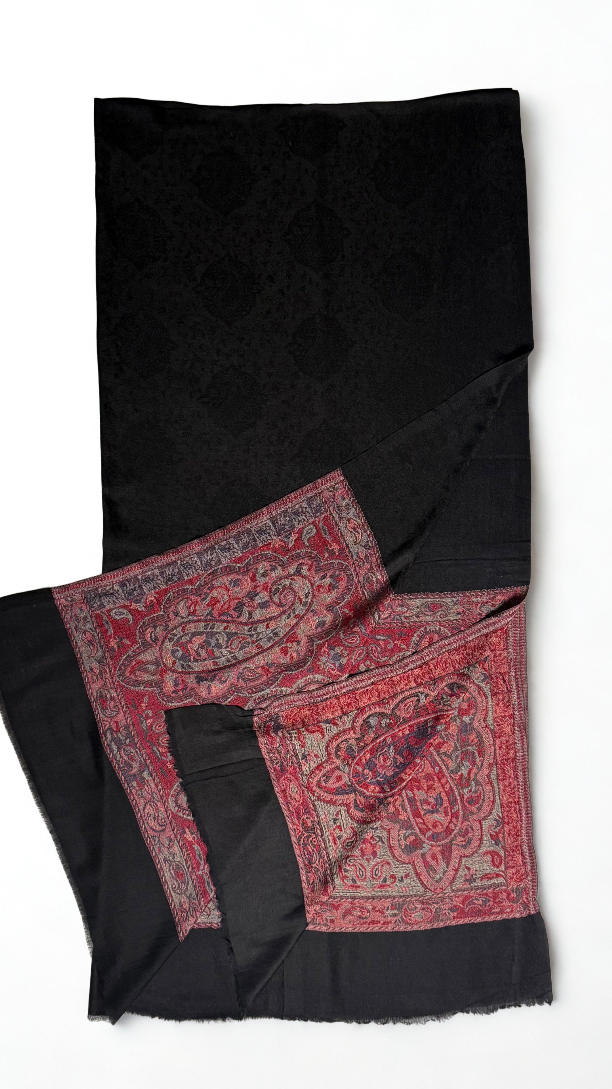 Close view of the large crimson paisleys woven on a silver field at the end of a black pashmina ring shawl