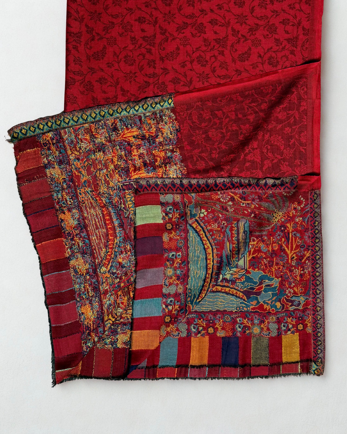 Woven landscape panel in blue, teal and saffron with houses, an arched bridge over water and palm trees on a ruby red ground