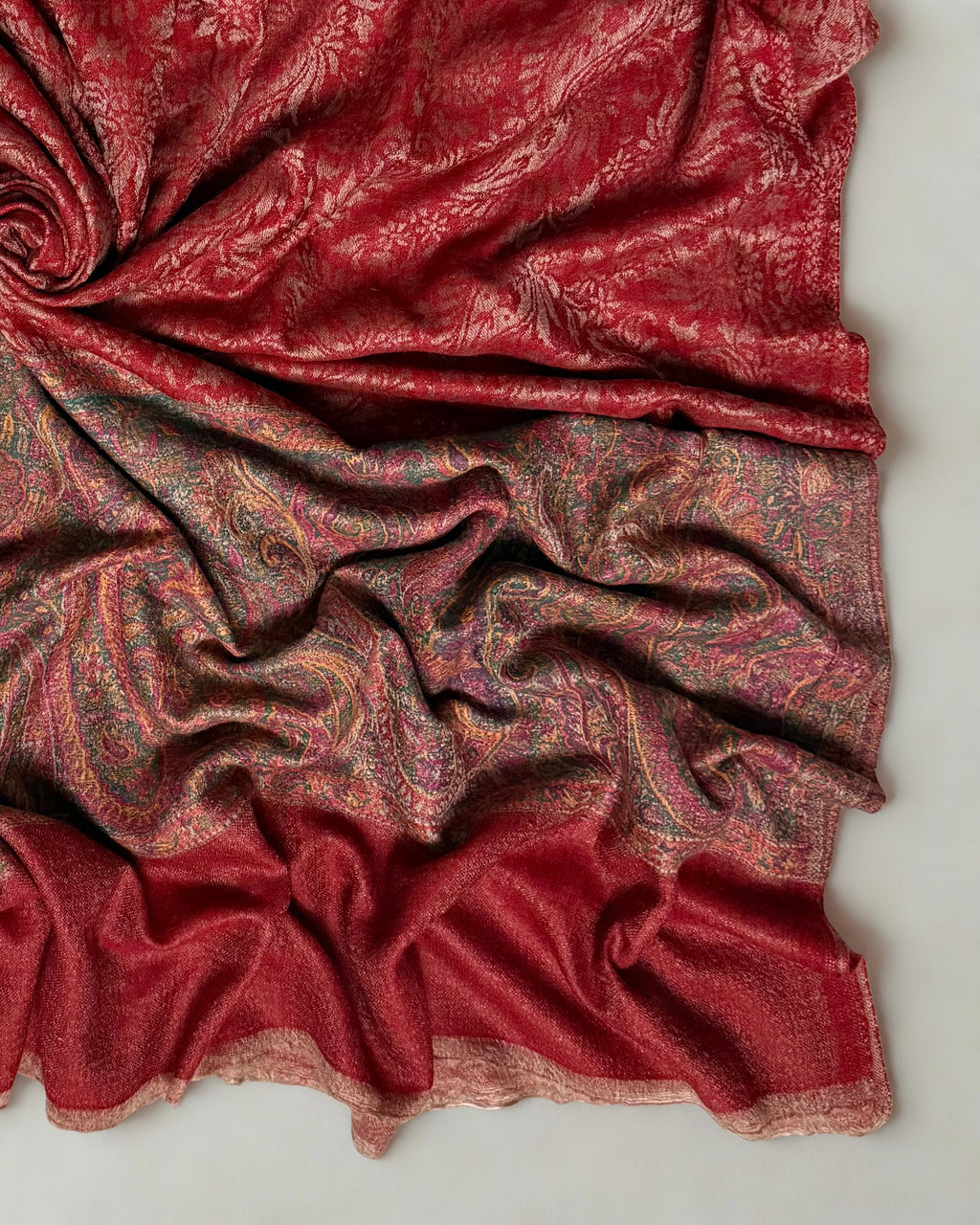 Brick red pashmina ring shawl folded flat, showing the paisley ground and border together