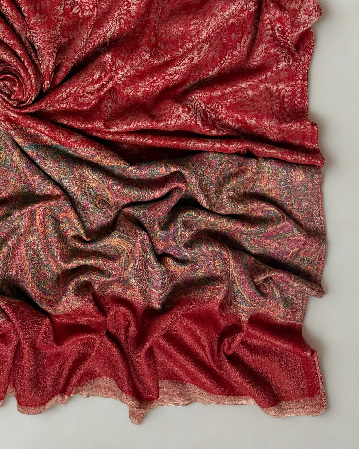 Brick red pashmina ring shawl folded flat, showing the paisley ground and border together