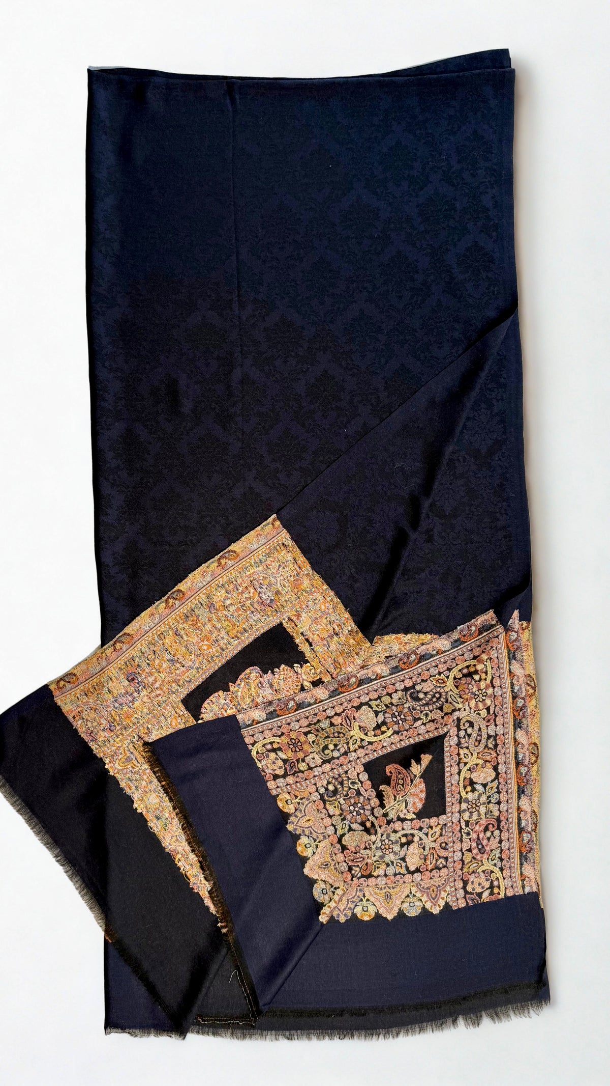Close view of the framed panel: outer paisley band, second band and a centre field of four upright flowering plants in old gold and rose