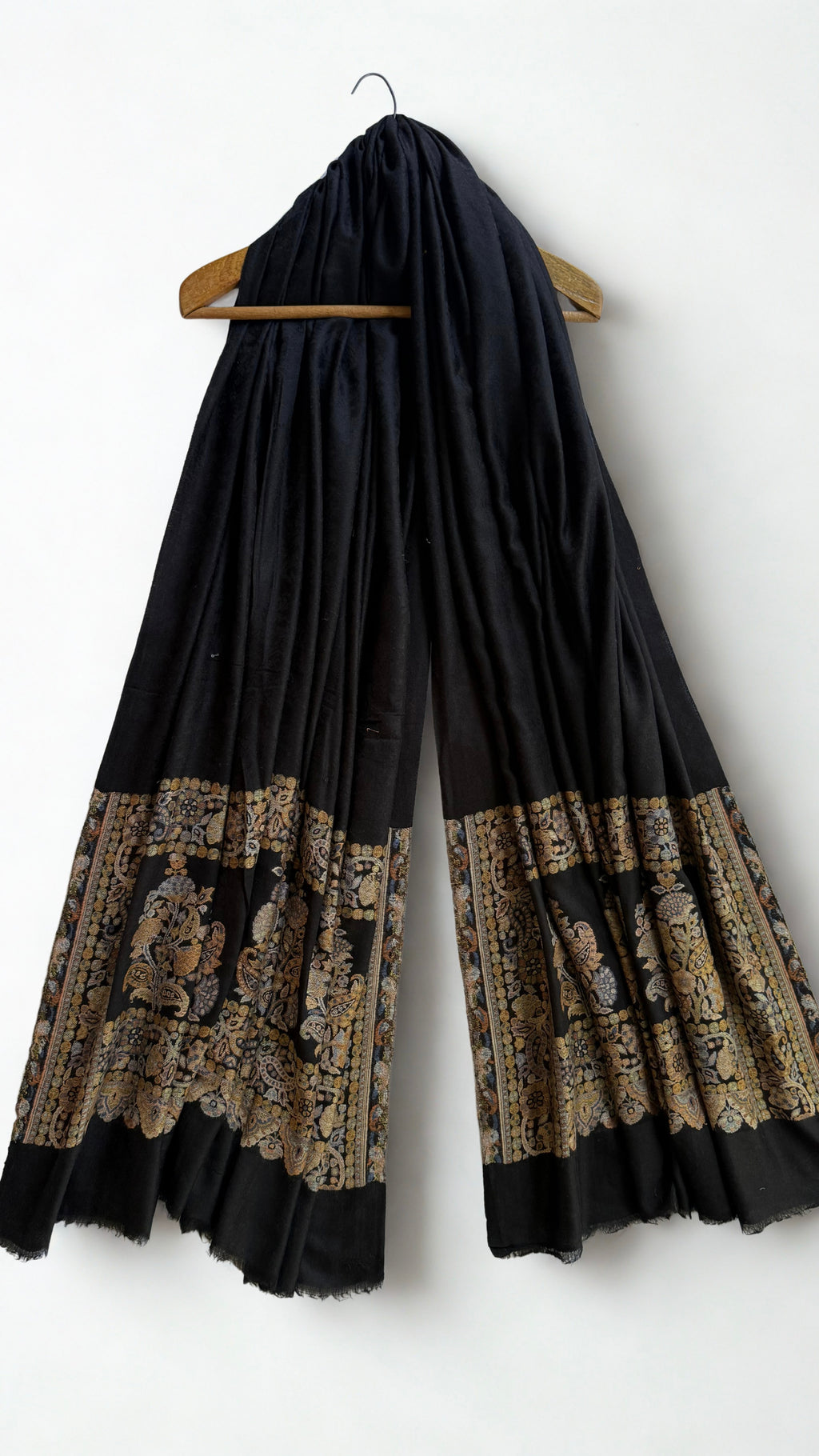 Black Palladar shawl on a wooden hanger showing both end panels and the fringed edge