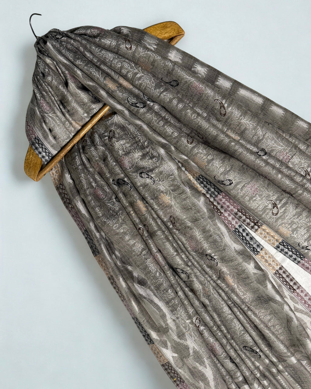 Silver grey jamawar shawl on a wooden hanger, showing its drape