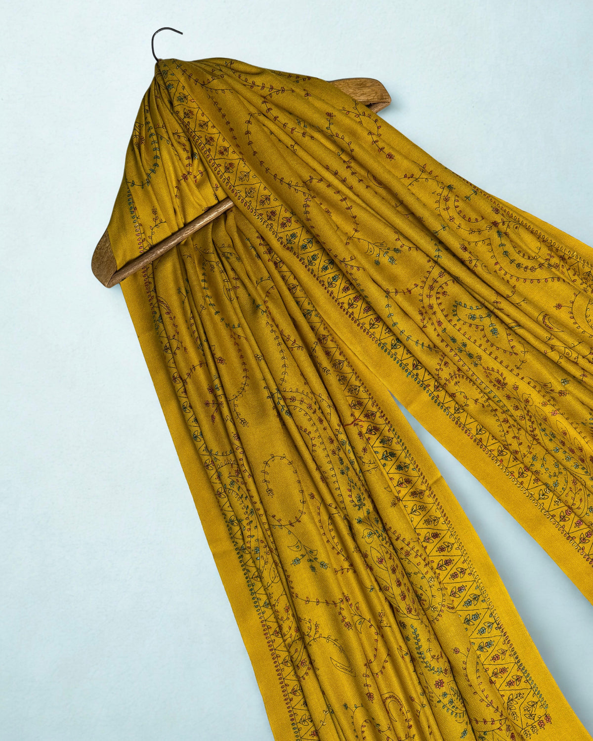 Mustard Swati Shahtoosh shawl on a wooden hanger, full hand embroidery from end to end