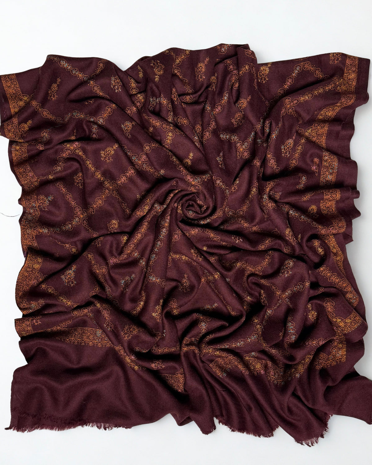 Wine Swati Shahtoosh shawl swirled to show the soft handle of the wool and the copper embroidery