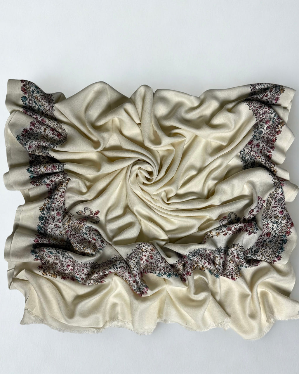 Full view of the white Swati Shahtoosh shawl gathered in a swirl, the wide hand-embroidered paisley border framing all four sides