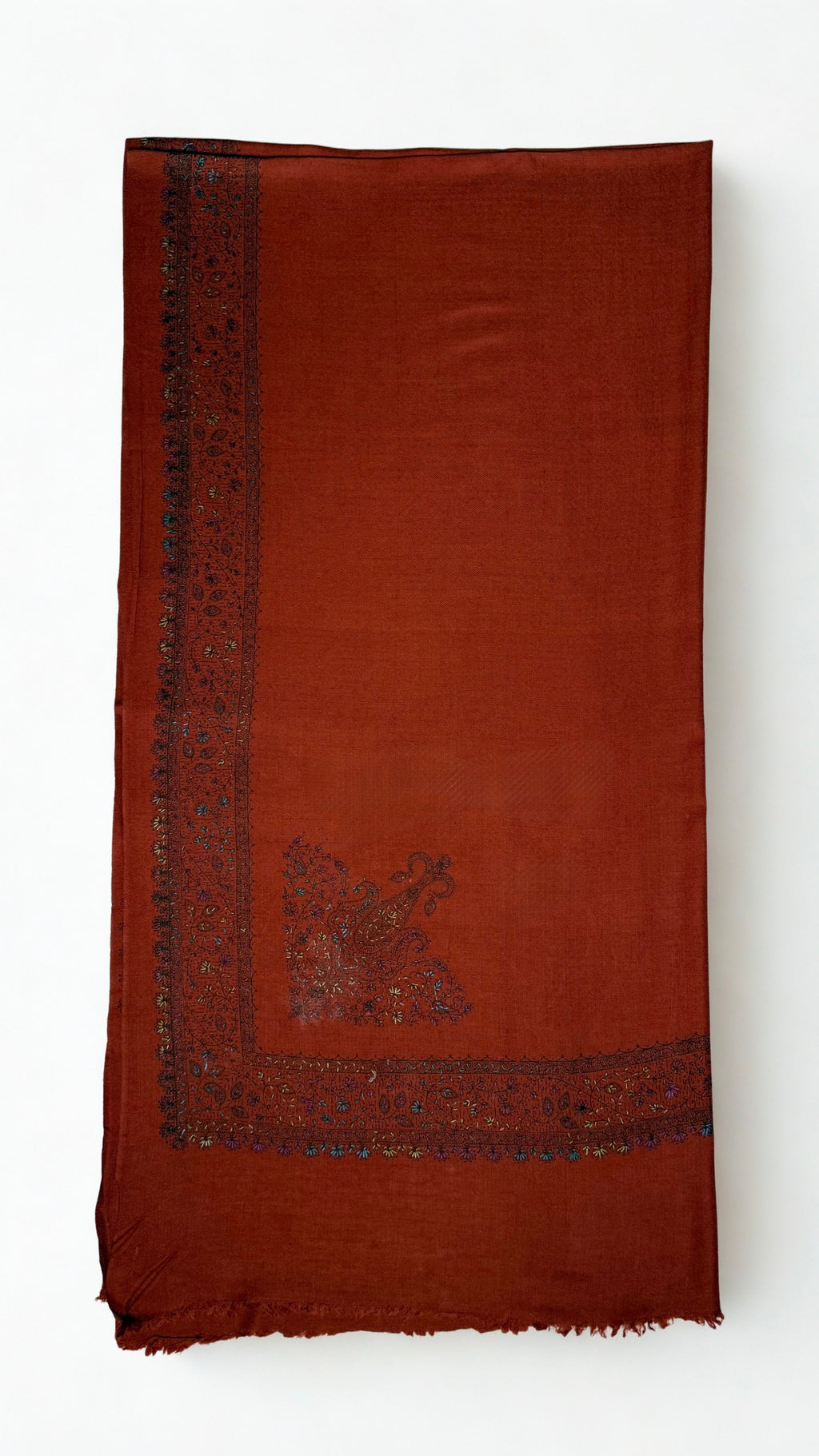 Rust Swati Shahtoosh shawl folded flat, the deep hand-embroidered vine border running down one edge with a large paisley at the corner