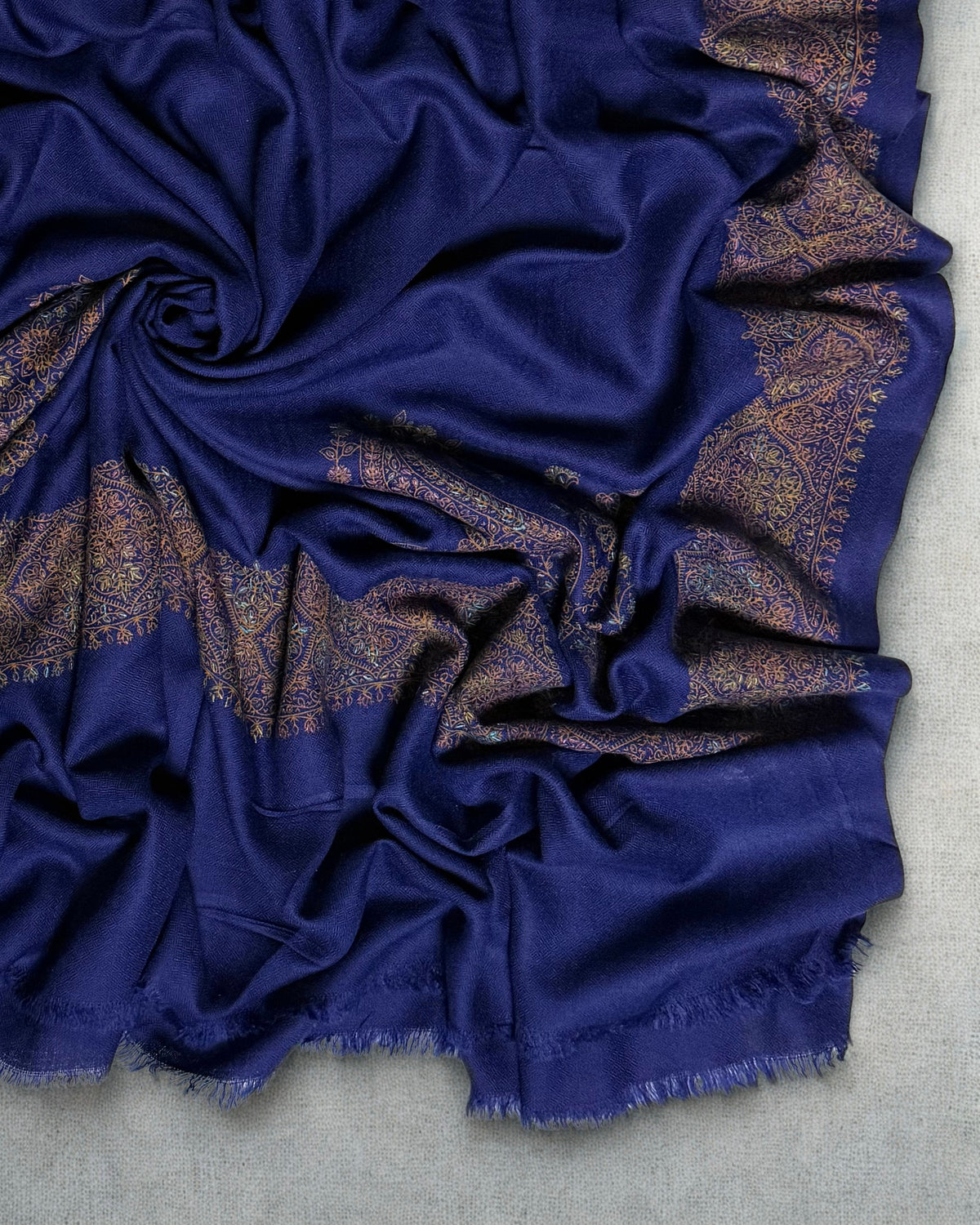 Navy Swati Shahtoosh shawl gathered in folds, showing the depth of the gold medallion border against the deep blue ground