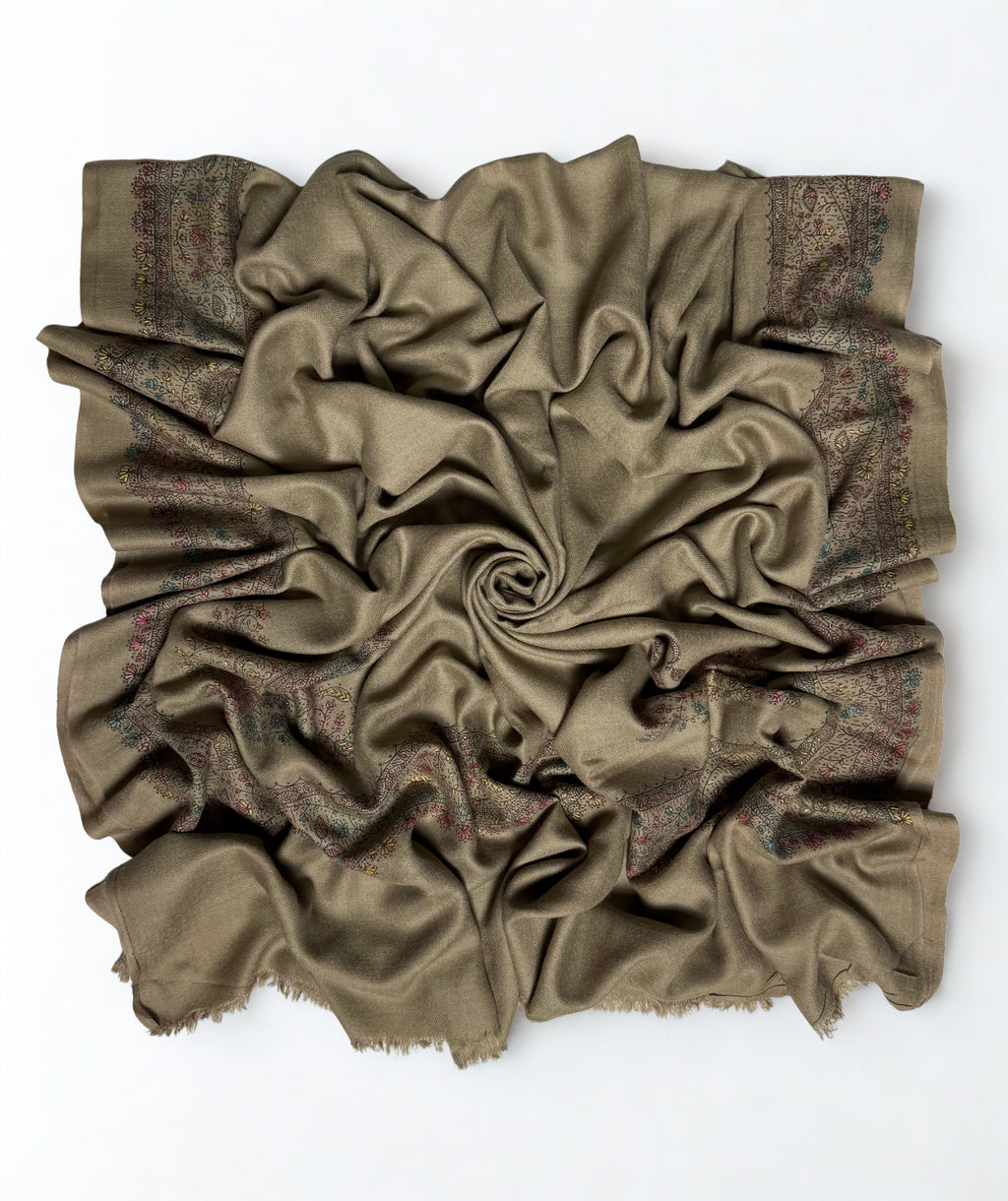 Grey Swati Shahtoosh shawl gathered in a swirl, the hand-embroidered floral vine border framing all four sides of the plain field