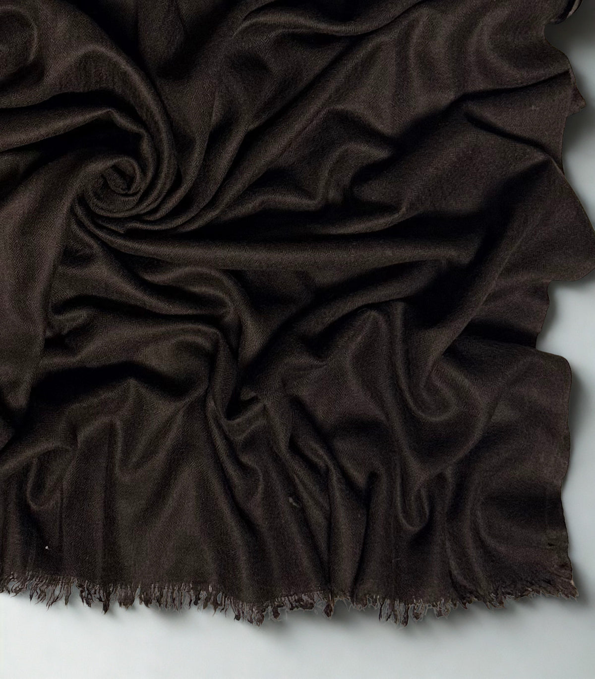 Close view of the espresso brown Swati Shahtoosh shawl in folds, showing the diamond weave texture and fringed edge