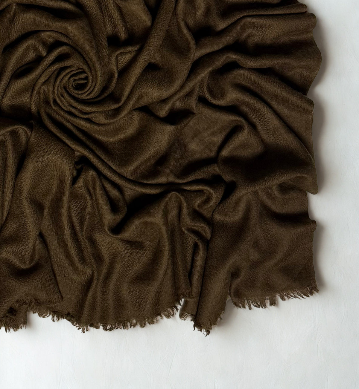 Close view of the warm brown Swati Shahtoosh shawl in folds, showing the diamond weave texture and fringed edge