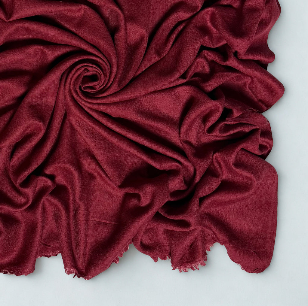 Close view of the maroon Swati Shahtoosh shawl in folds, showing the diamond weave texture and fringed edge