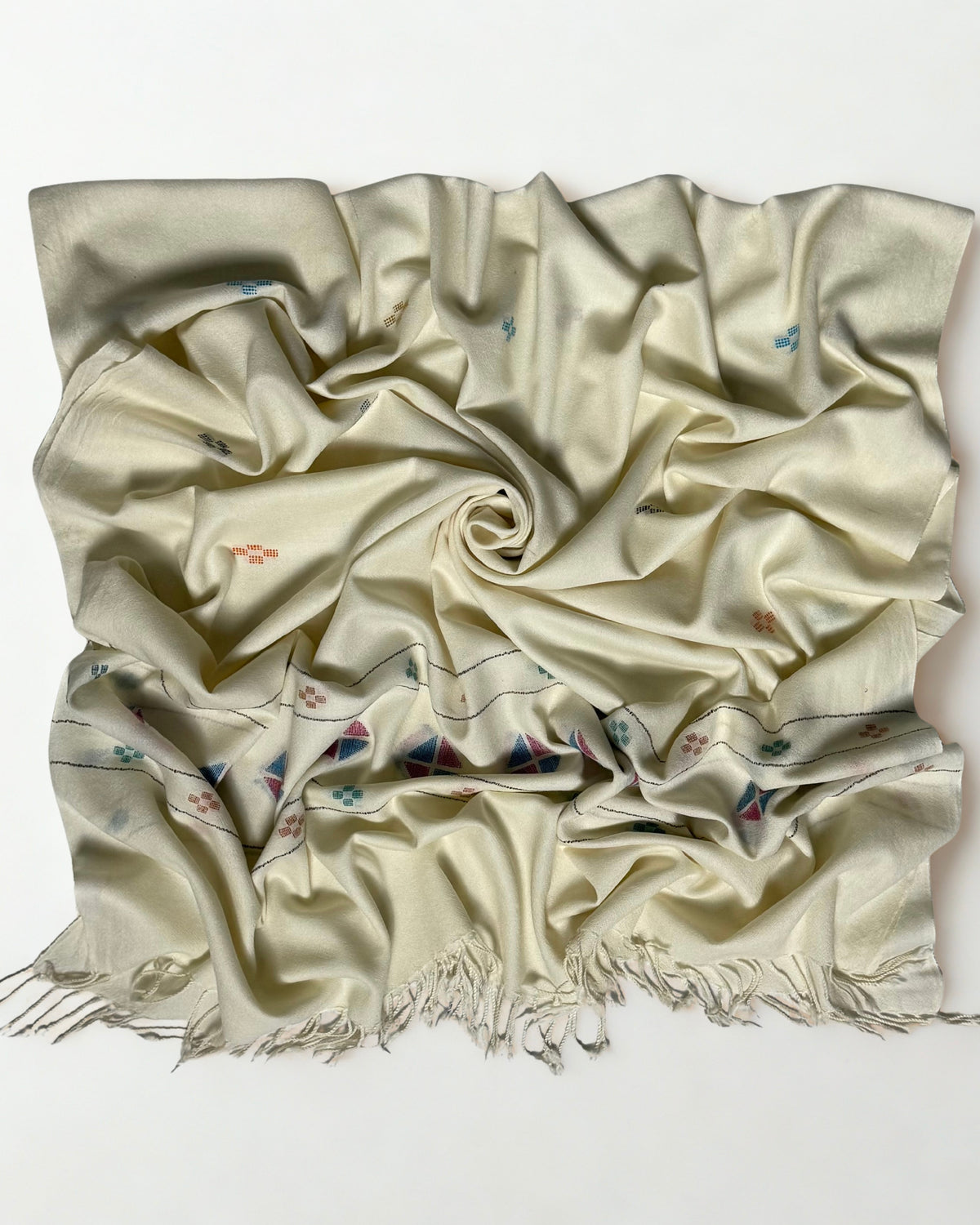 Off-white Khadi Swati Shahtoosh shawl gathered in a swirl, the soft cloth catching light with woven buti scattered across the folds