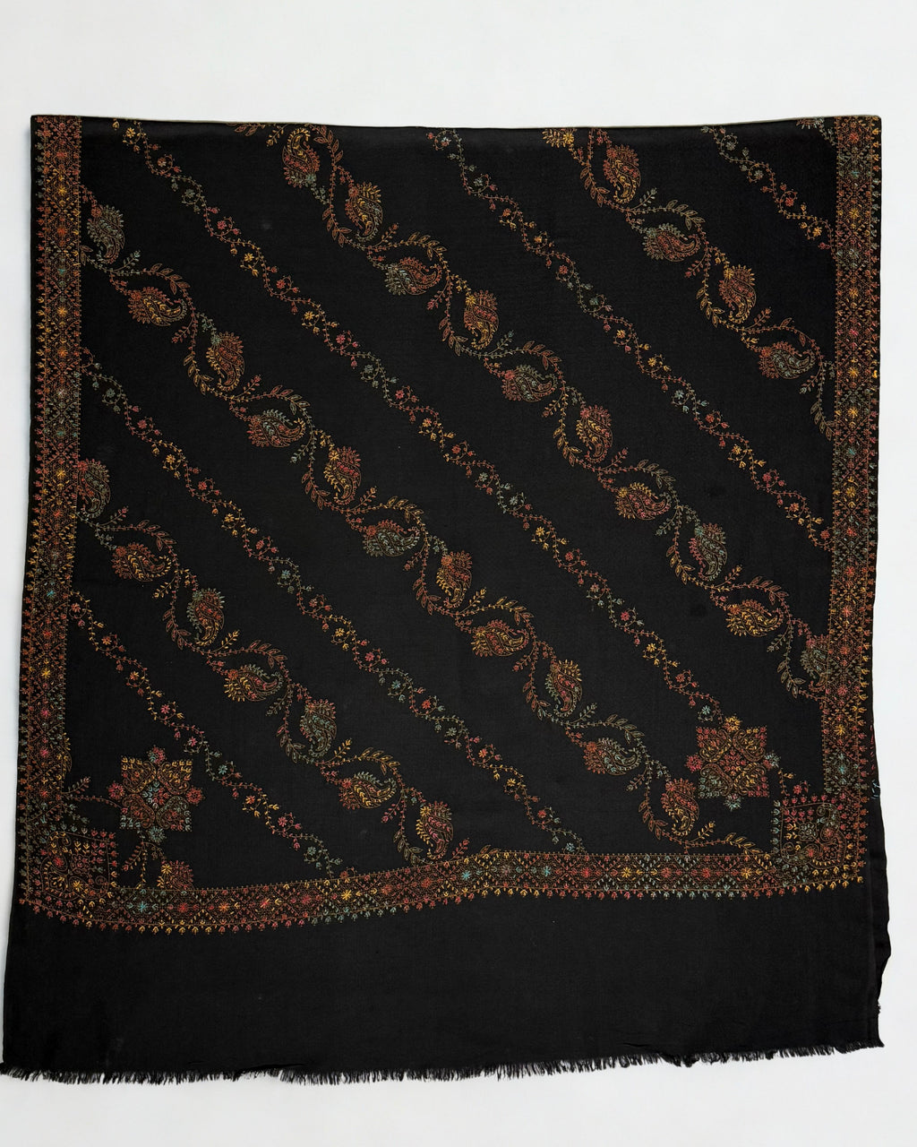 Black Swati Shahtoosh shawl laid flat, full diagonal paisley jaal in rust, ochre, gold and teal with two embroidered corner medallions and border