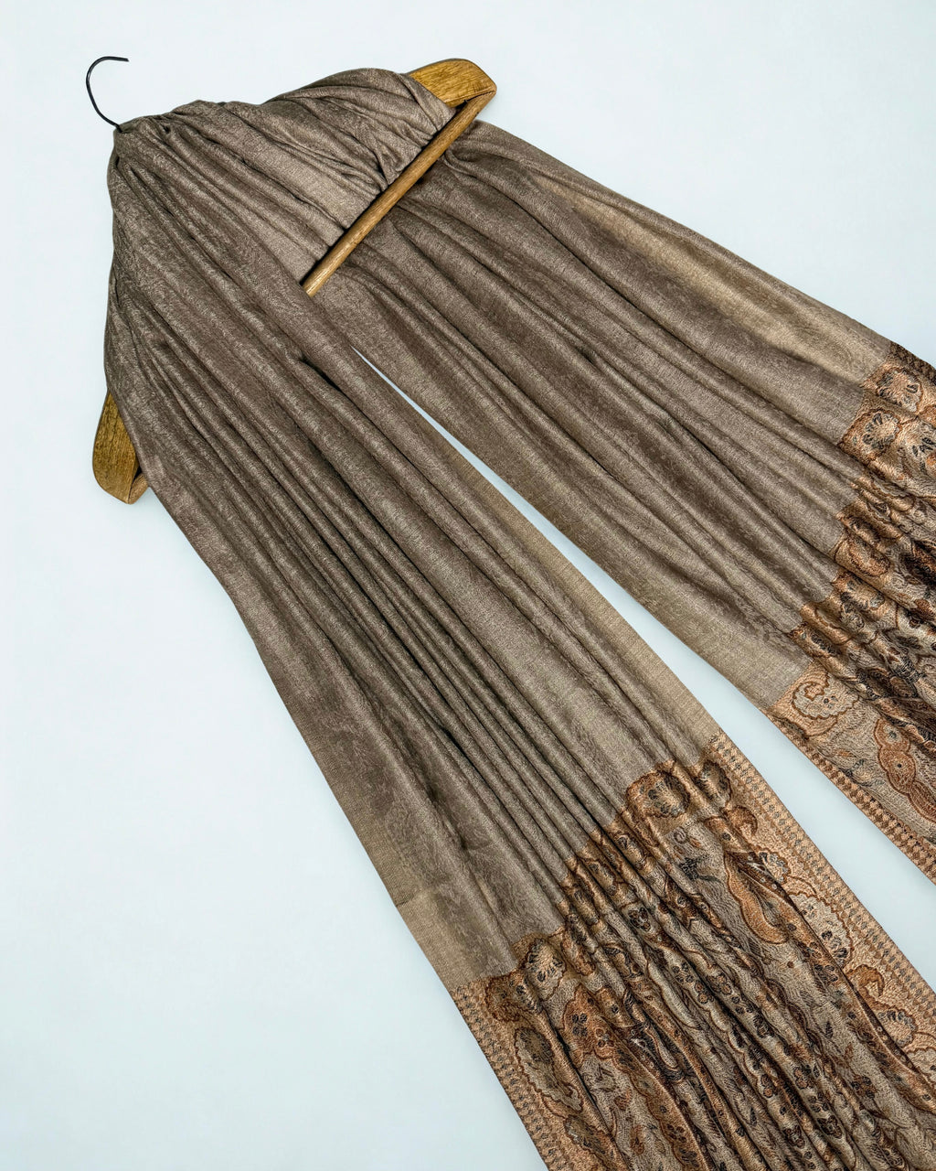 Warm khaki Palladar shawl draped on a hanger at an angle, showing the soft sheen of the field and the paisley pallas