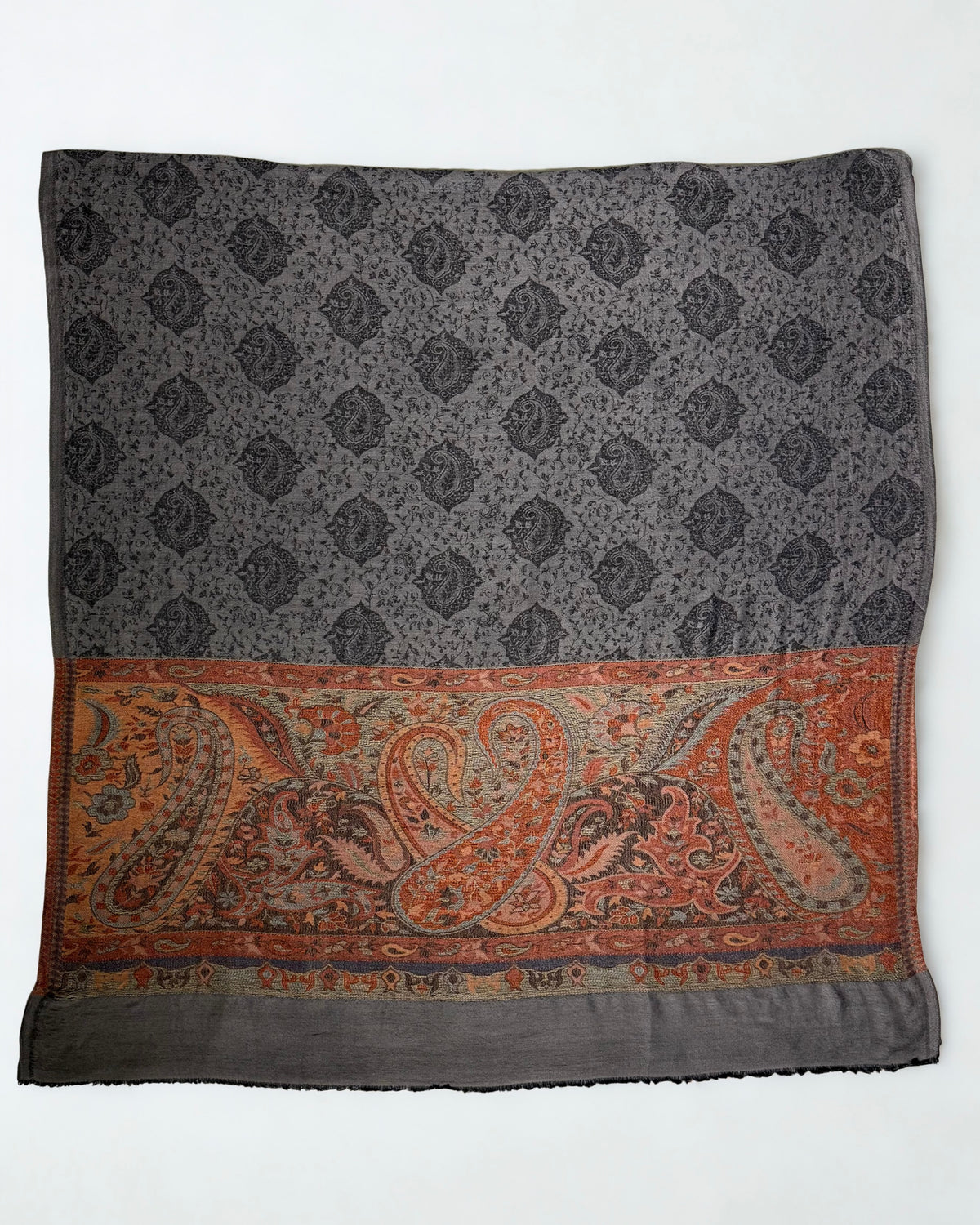 Charcoal pashmina ring shawl laid flat, showing rows of black paisley medallions and the full width of the rust paisley pallu
