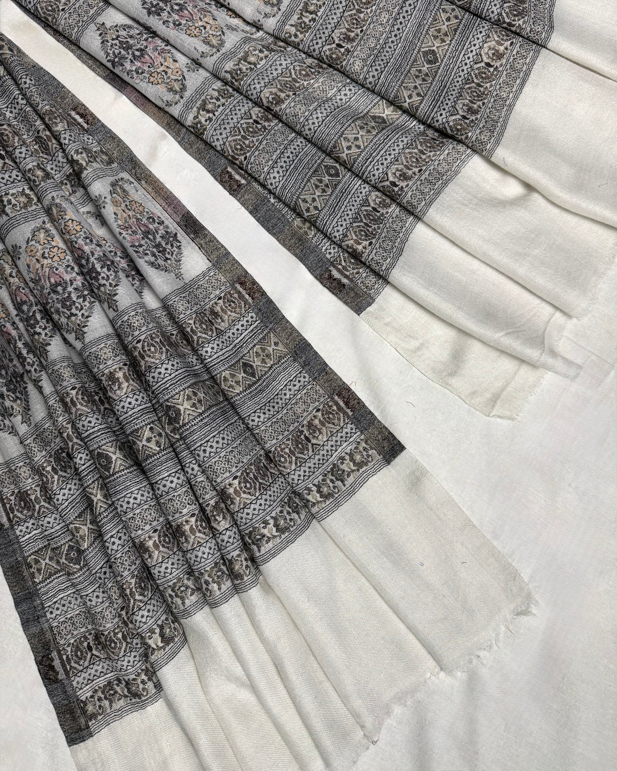 Detail of the paisley buta rows and fine geometric stripes woven in grey and stone on ivory pashmina