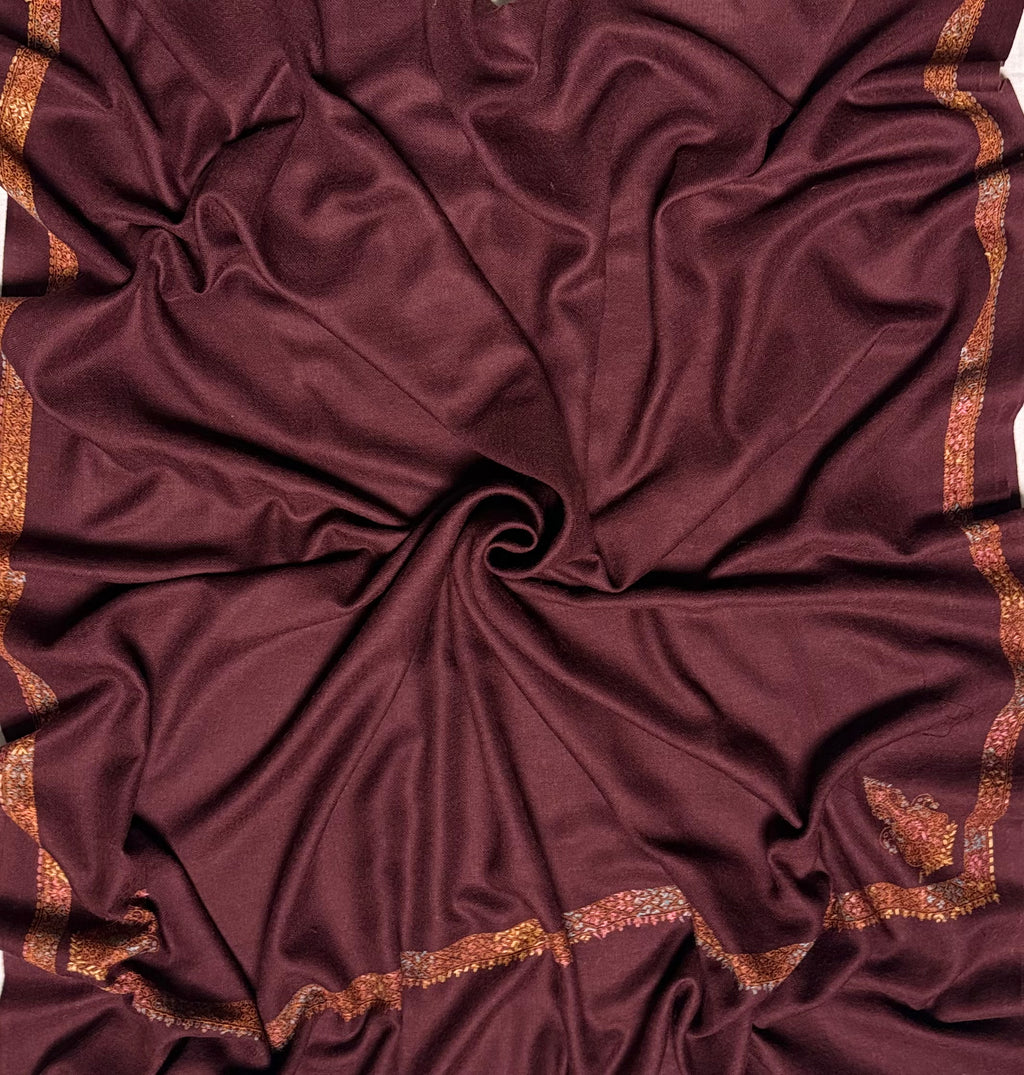 Close view of the gold and rust hand embroidery against the deep maroon lattice-woven ground