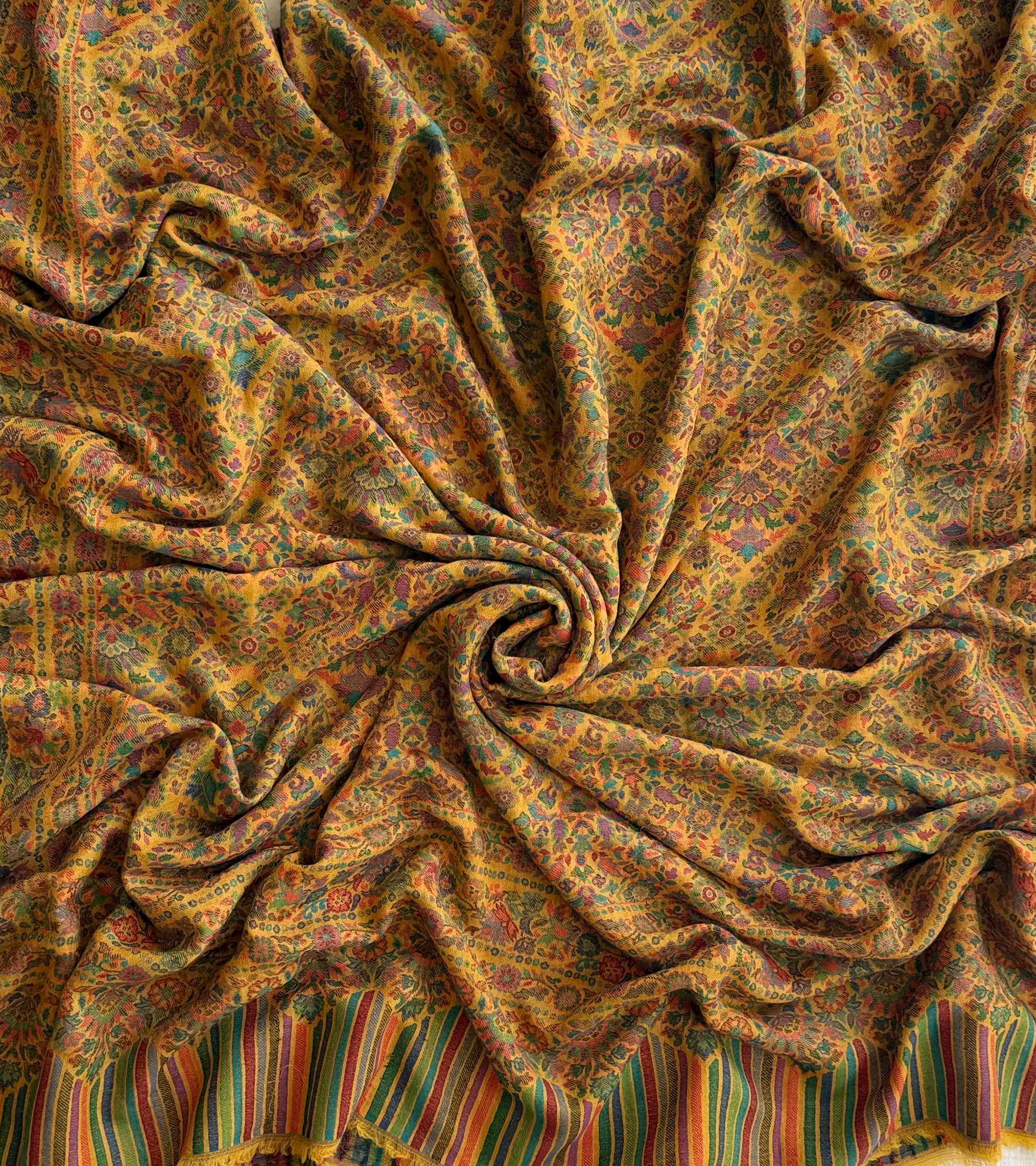 Close view of the teal, rose and violet flowering medallions woven into a marigold pashmina ground