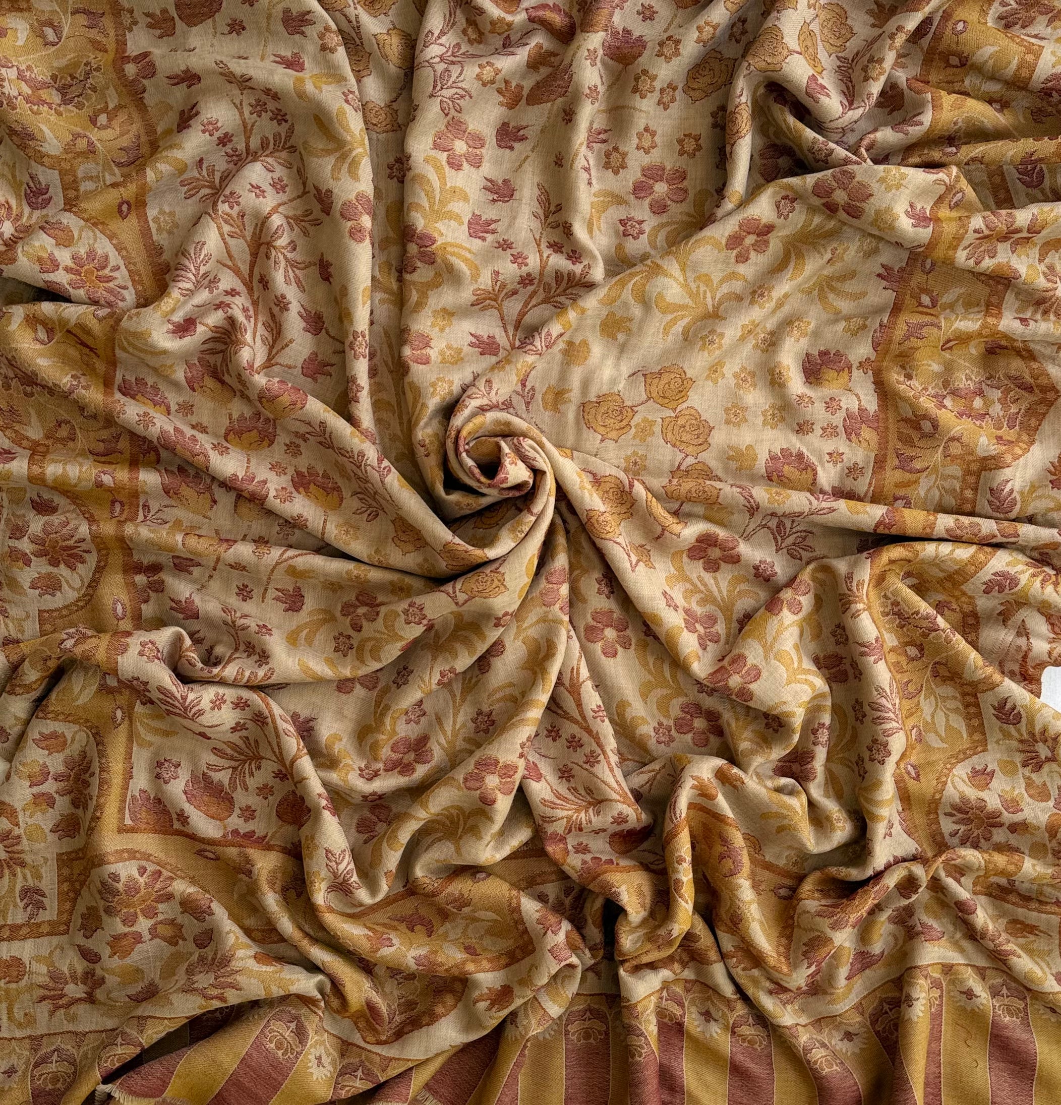 Sand and rose Kani pashmina shawl swirled open, showing the drape and the soft three-tone floral weave