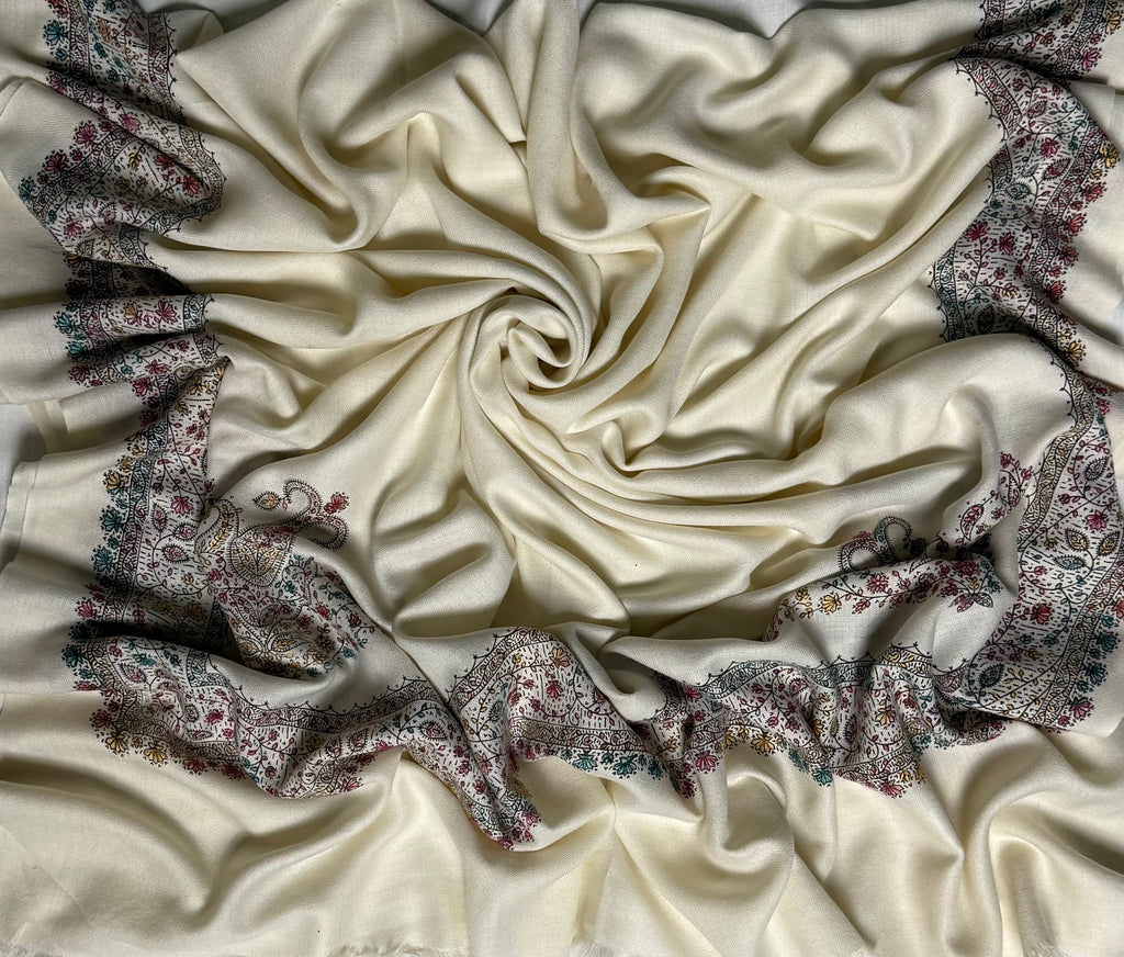 Close view of the hand-embroidered border on the white Swati Shahtoosh shawl, showing fine paisley and floral stitching in maroon, teal, gold and charcoal on soft ivory wool