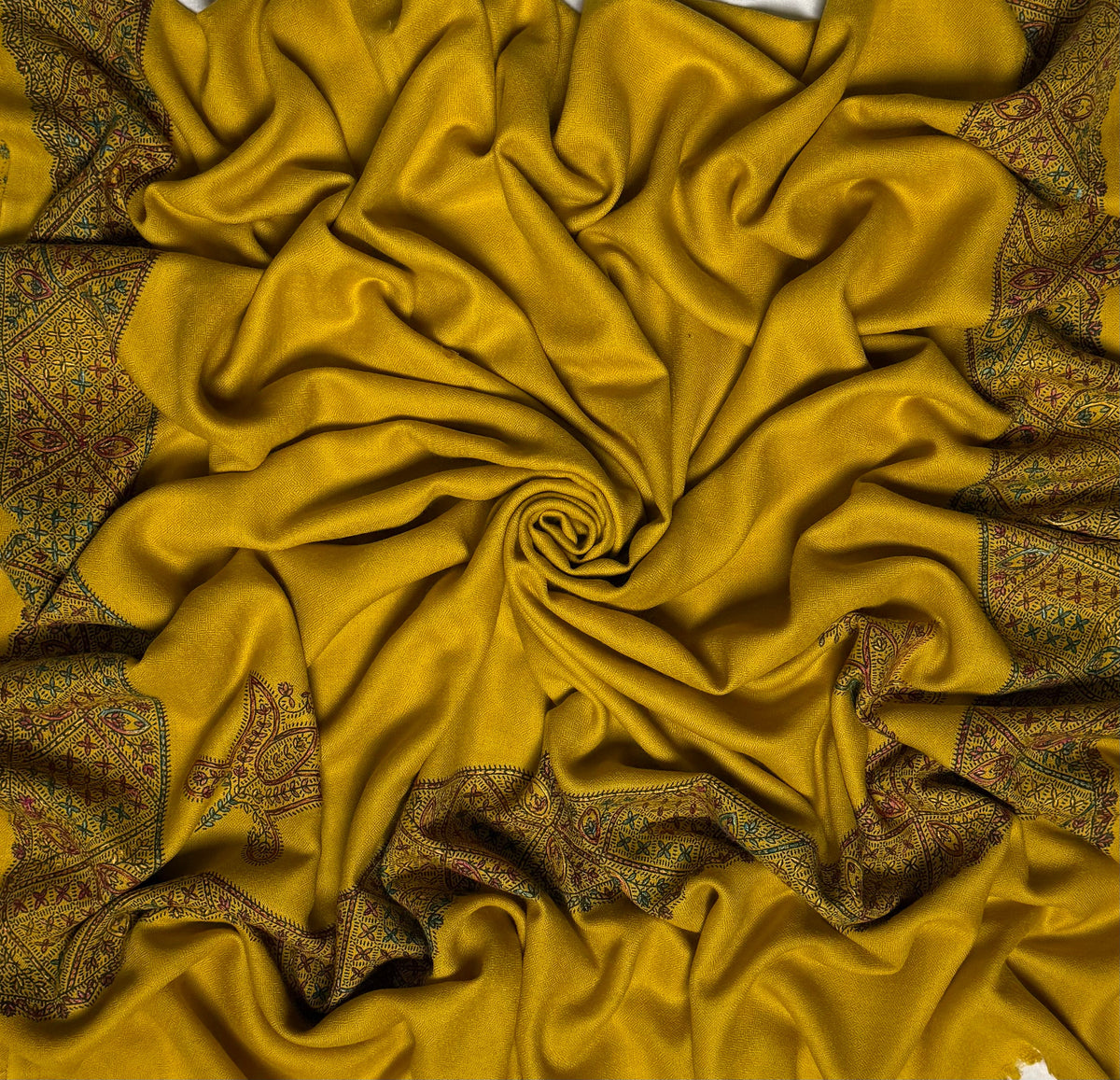 Close view of the mustard Swati Shahtoosh shawl, showing the hand-embroidered jali lattice border in rust, teal and rose against the self-coloured diamond weave