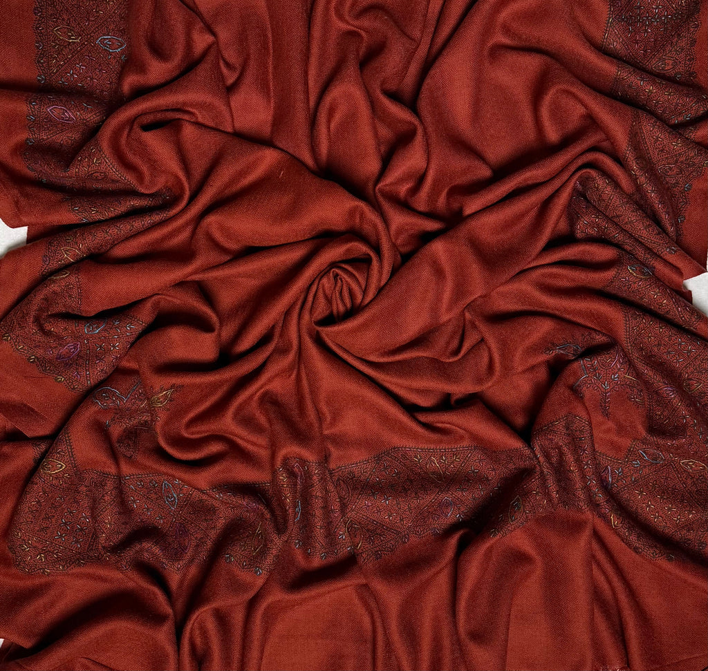 Close view of the rust Swati Shahtoosh shawl, showing the hand-embroidered lattice border and the self-coloured diamond weave of the ground