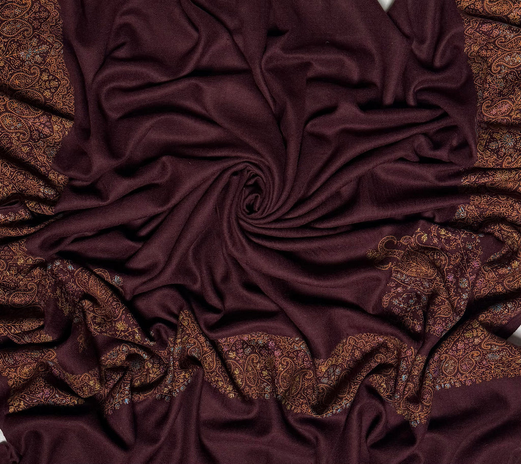 Close view of the deep maroon Swati Shahtoosh shawl, showing the hand-embroidered paisley border in gold, copper and pastel thread against the self-coloured lattice of the ground