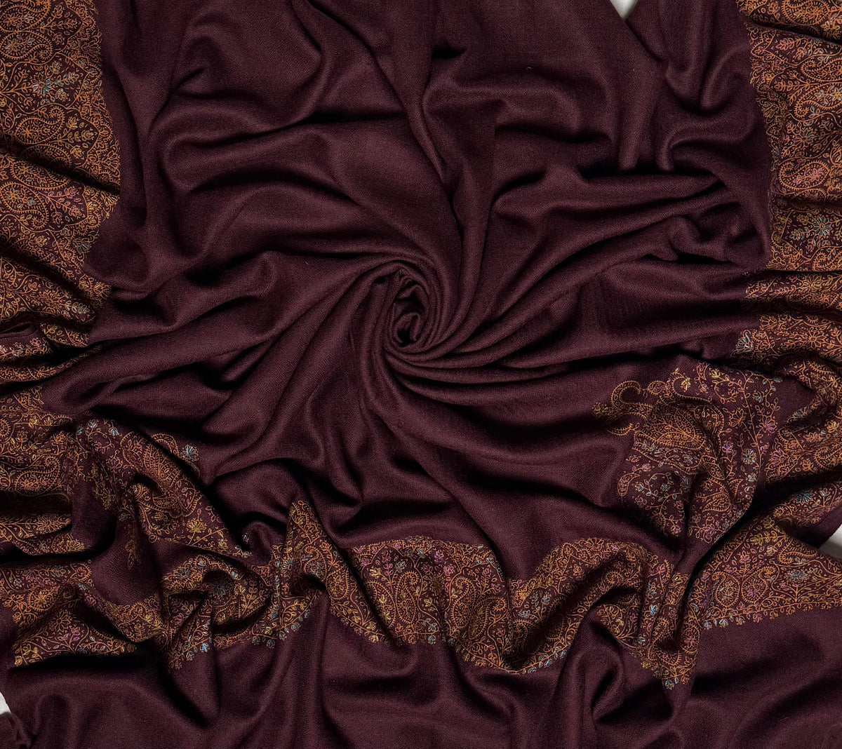 Close view of the deep maroon Swati Shahtoosh shawl, showing the hand-embroidered paisley border in gold, copper and pastel thread against the self-coloured lattice of the ground