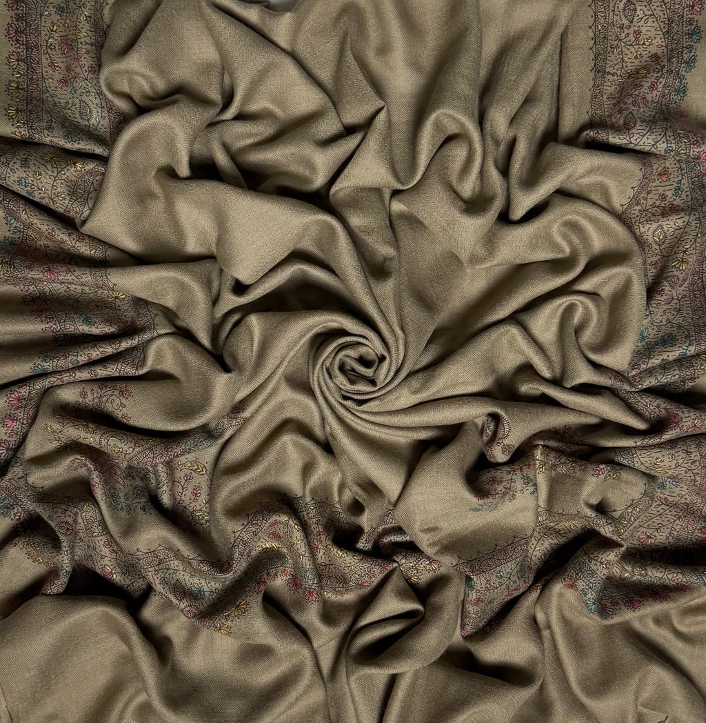 Close view of the grey Swati Shahtoosh shawl, showing the hand-embroidered floral vine border in faded teal, rose and citron against the self-coloured herringbone weave