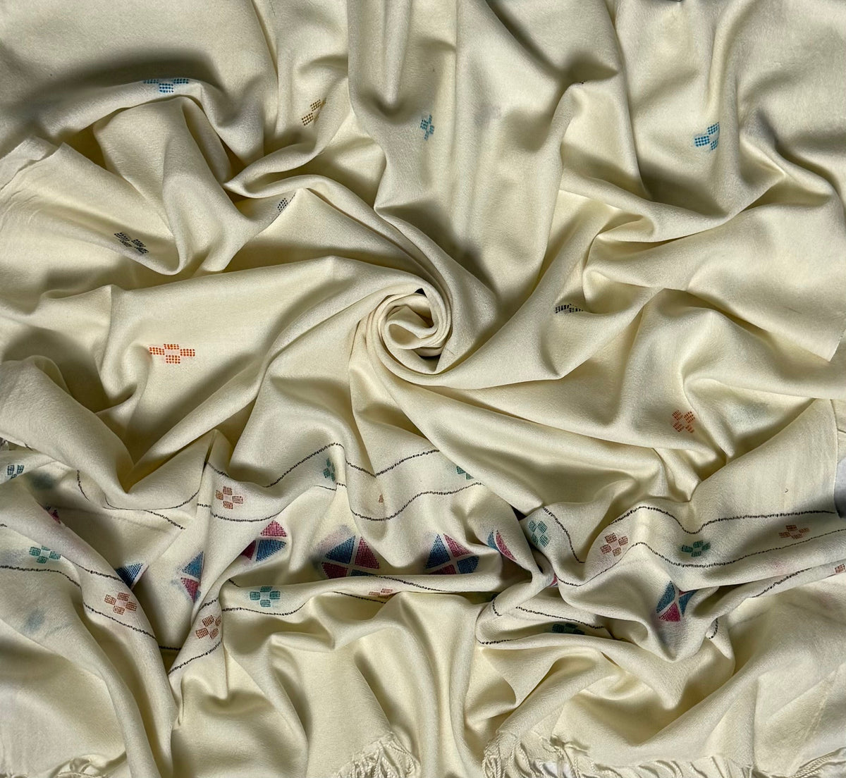 Close view of the off-white Khadi Swati Shahtoosh shawl, showing the woven diamond medallion and flower buti border and twisted fringe