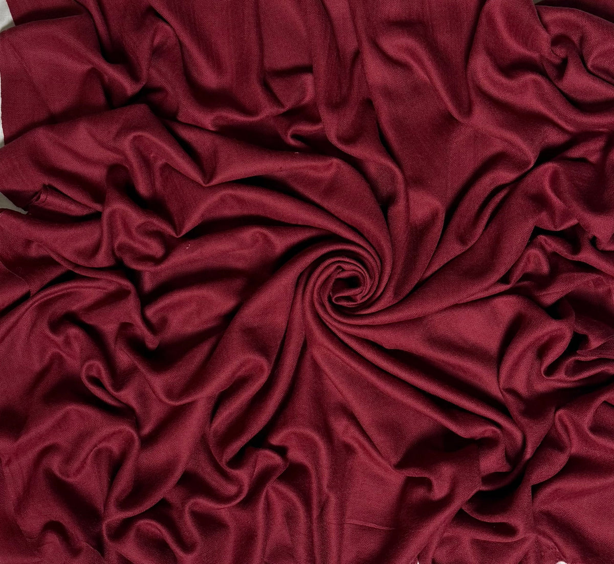 Close view of the maroon Swati Shahtoosh shawl, showing the self-coloured diamond weave and fringed end