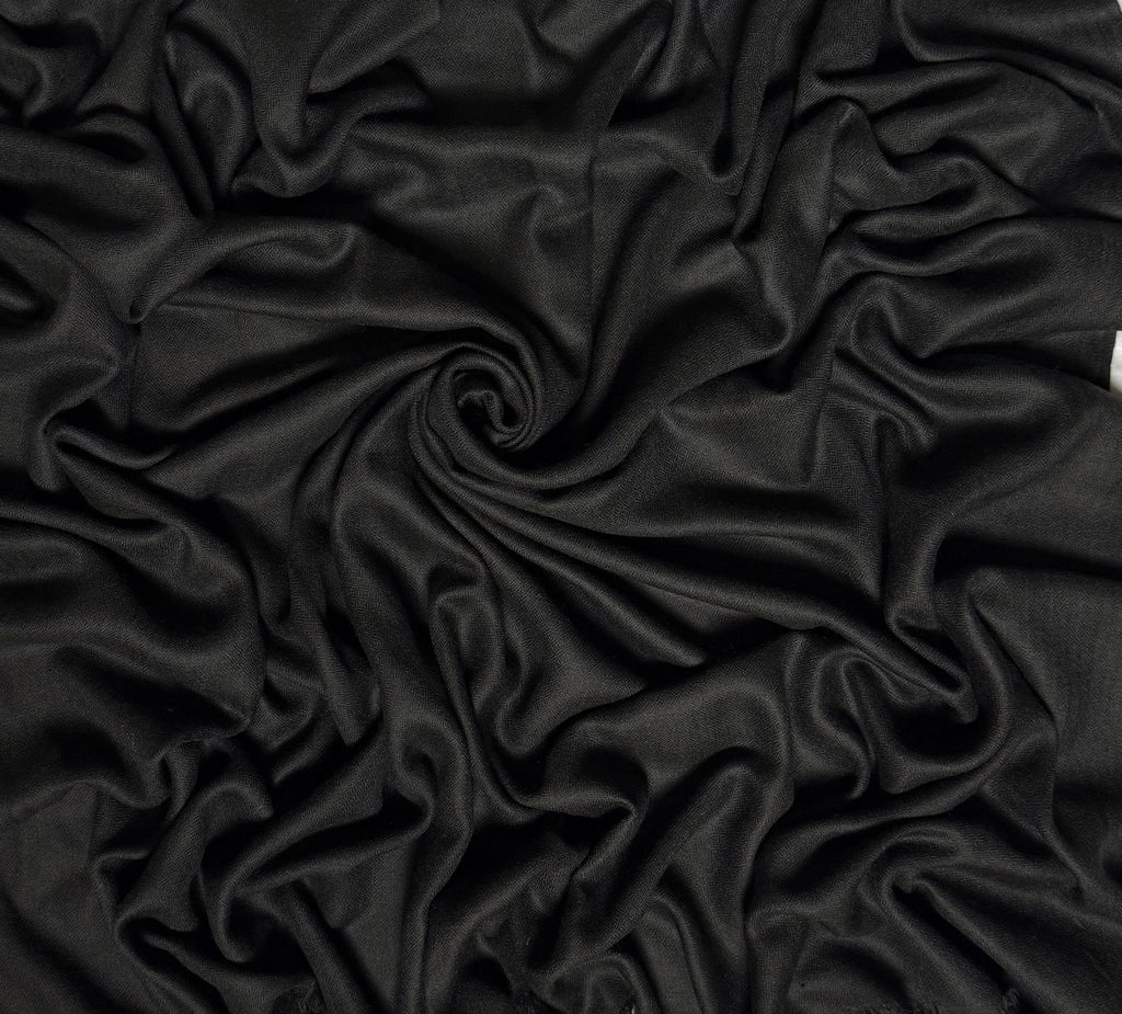 Close view of the charcoal black Swati Shahtoosh shawl, showing the self-coloured diamond weave and fringed end
