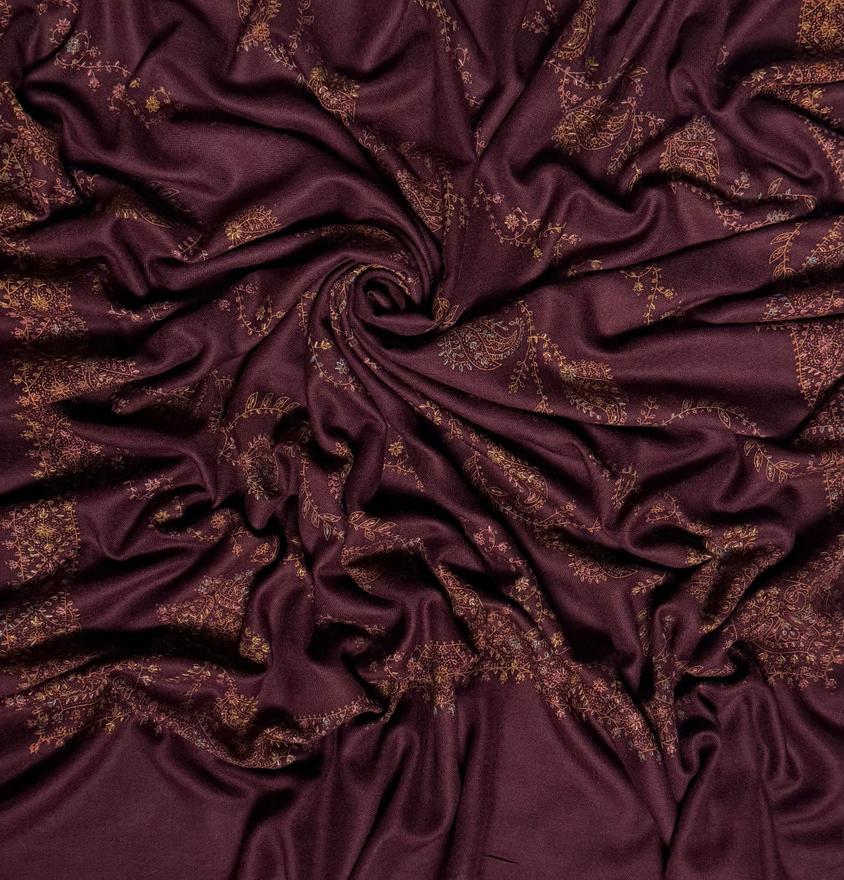 Deep maroon Swati Shahtoosh shawl draped in a swirl, showing the full spread of hand embroidery across the cloth