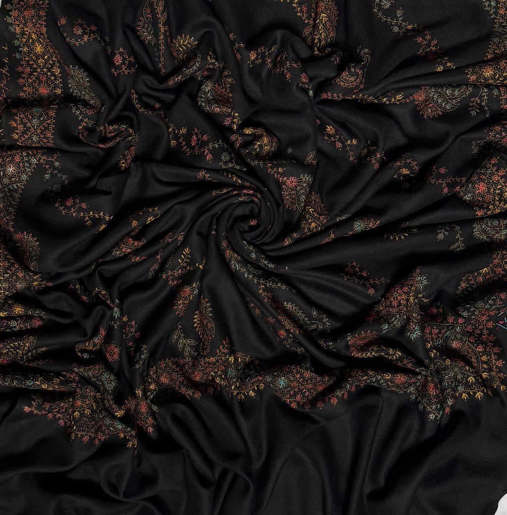 Black Swati Shahtoosh shawl swirled from above, showing the full spread of multicolour hand embroidery across the cloth