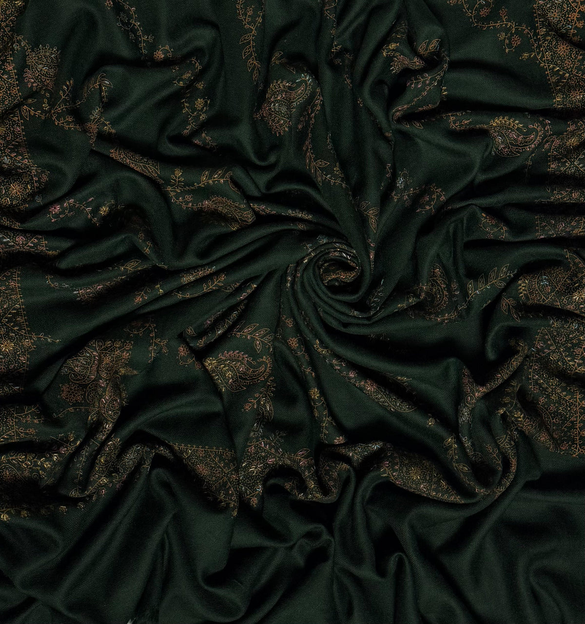 Forest green Swati Shahtoosh shawl draped in a swirl, showing the full spread of hand embroidery across the cloth