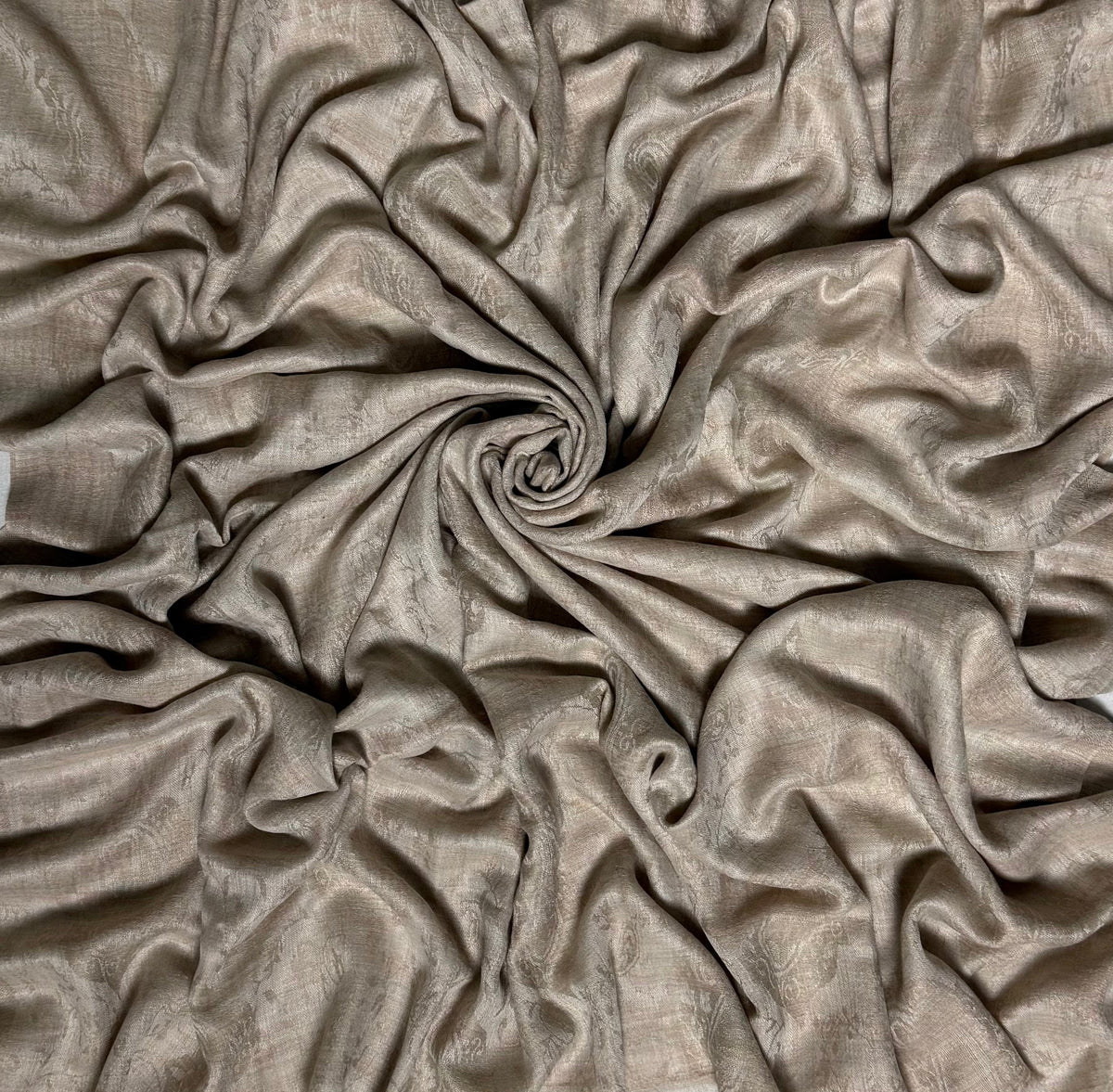 Close-up of a stone taupe fine pashmina shawl swirled to show the sheen and texture of the cloth