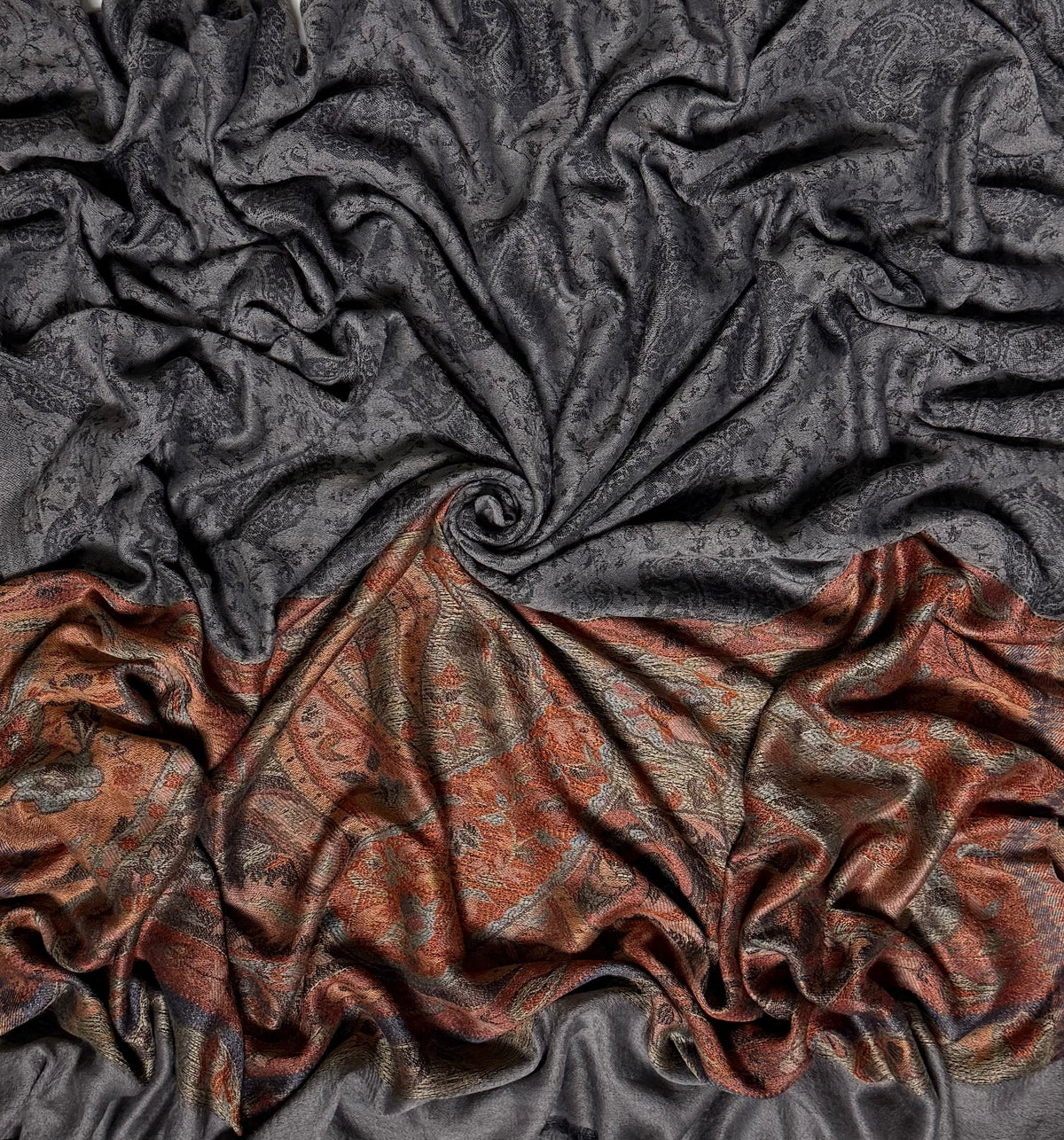 Charcoal Palladar shawl swirled to show the sheen of the fine pashmina and the woven rust paisley end