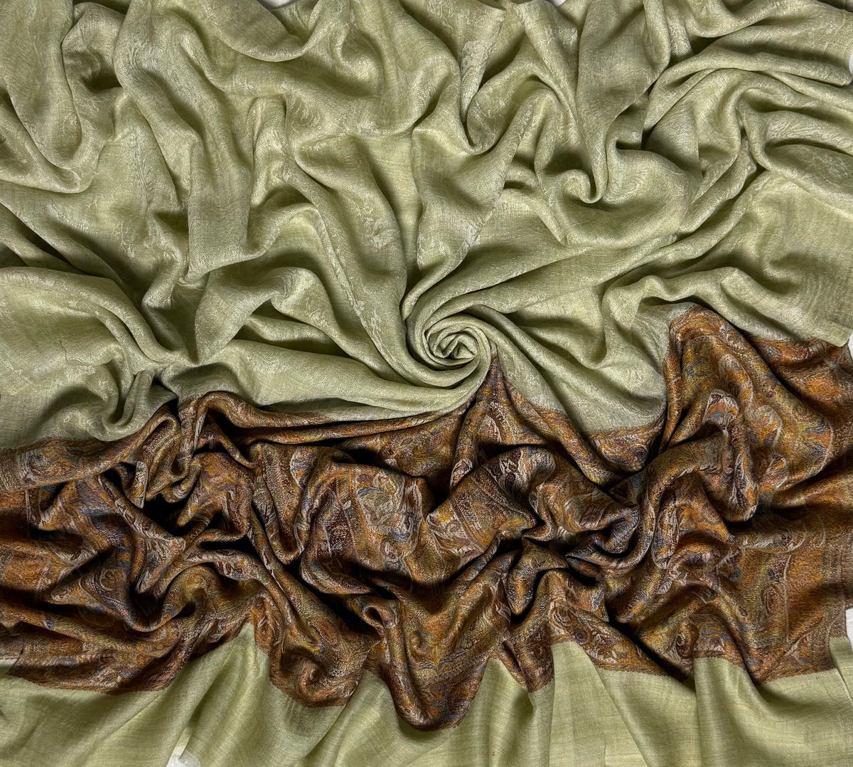 Pistachio Palladar shawl swirled to show the sheen of the fine pashmina and the rich bronze woven end