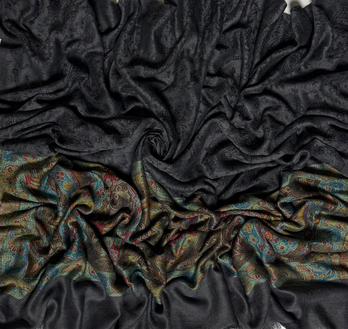 Dark charcoal Palladar shawl swirled to show the sheen of the fine pashmina and the woven jewel-tone paisley end