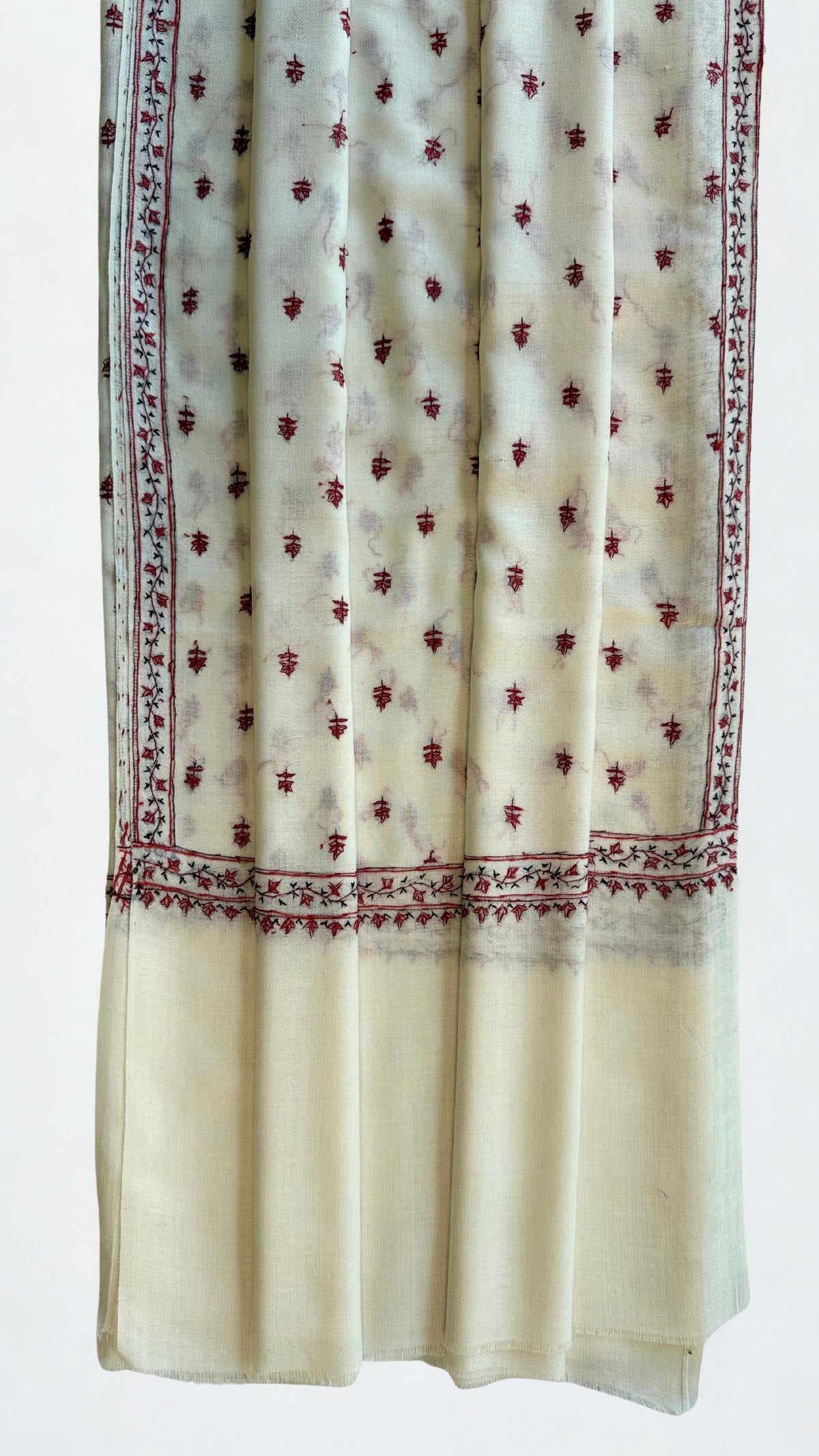 Close view of the crimson hand embroidery and reverse thread-work on an ivory pashmina shawl