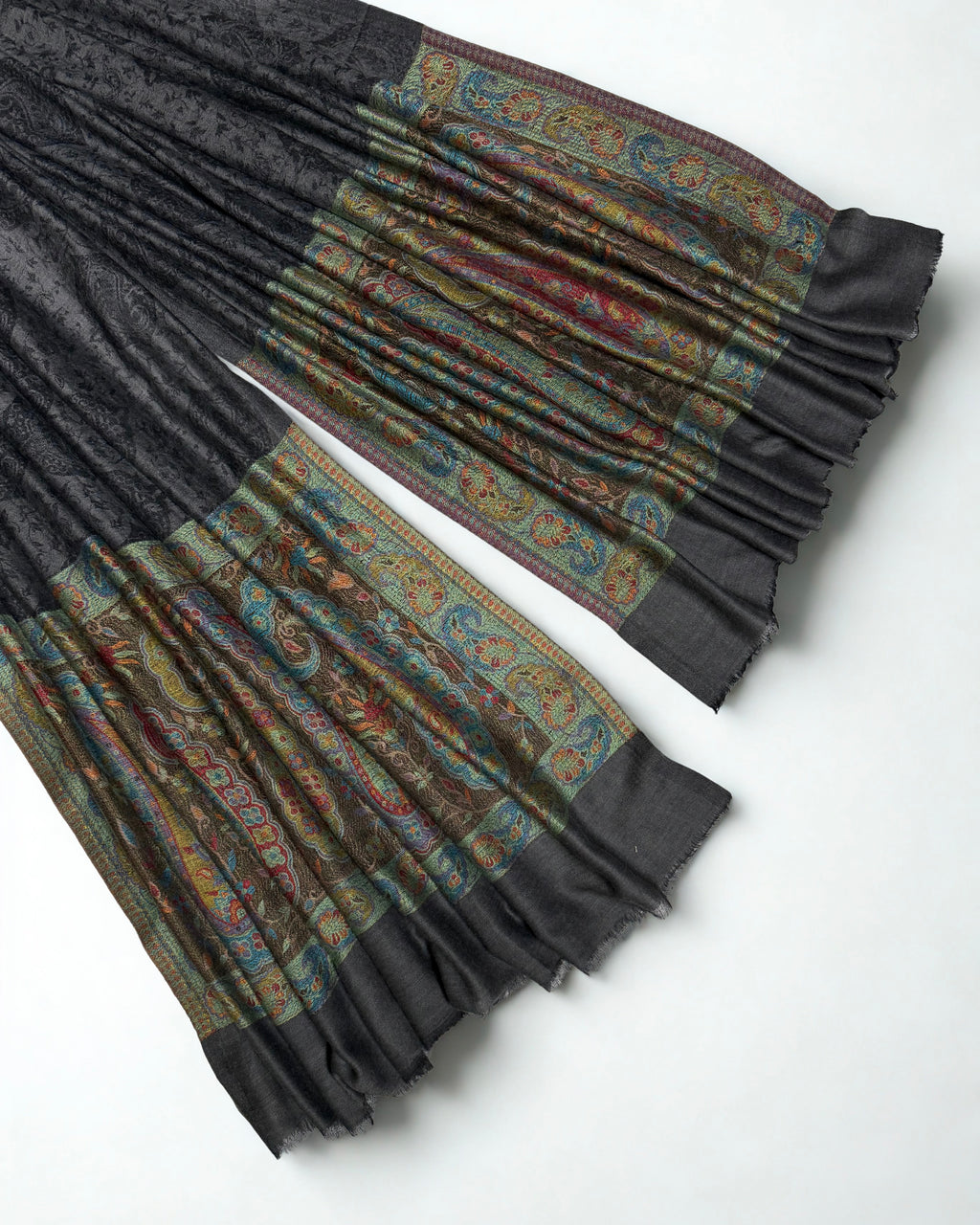 Close-up of both ends of a dark charcoal pashmina ring shawl, showing the teal, crimson, saffron and sage woven paisley pallas