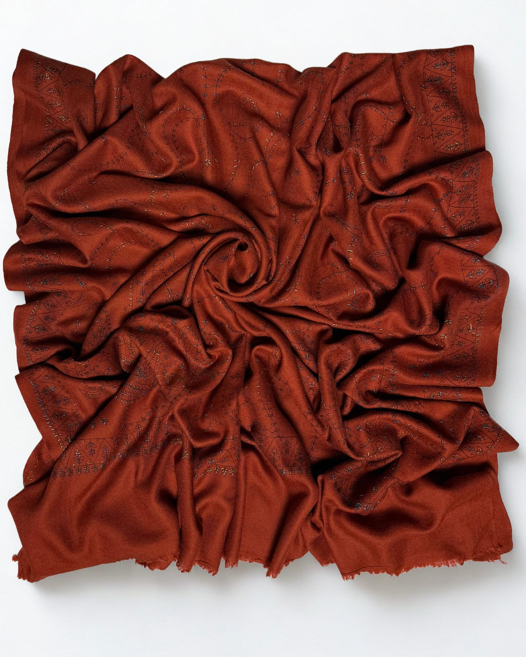 Rust Swati Shahtoosh shawl swirled to show the soft handle of the wool and the fine embroidery
