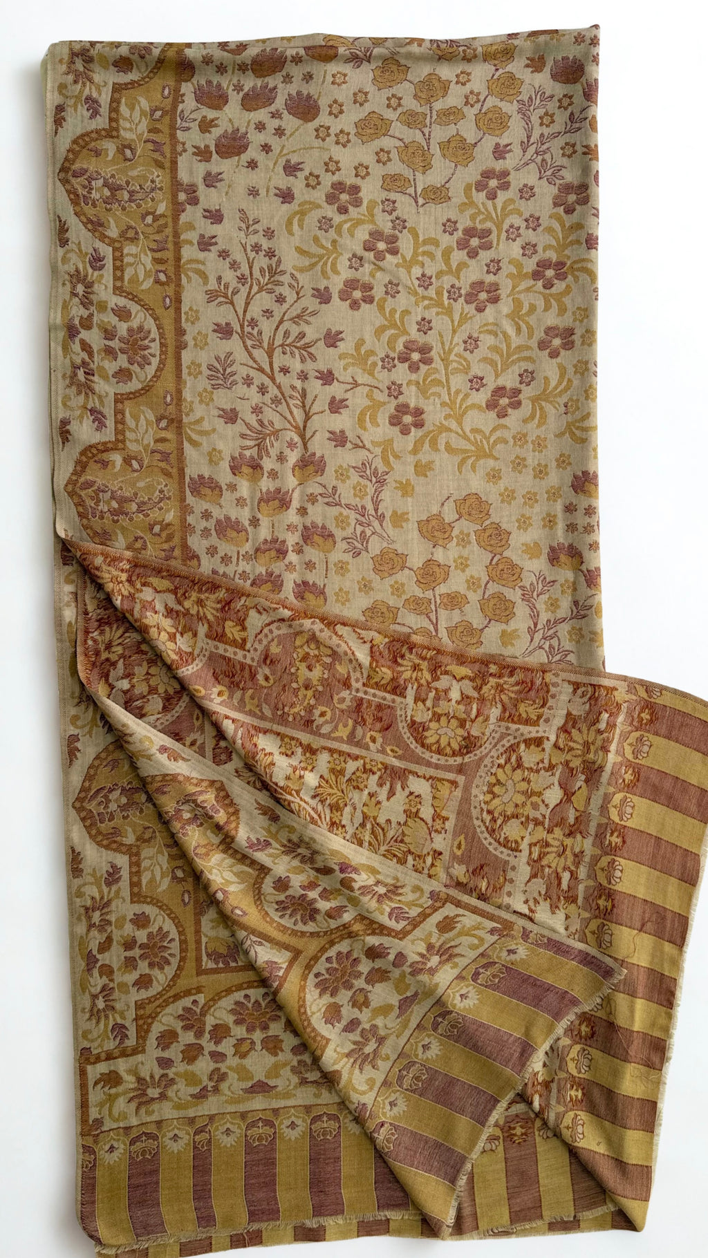 Sand Kani pashmina shawl laid flat, rose and ochre flowering sprays framed by a scalloped border with a striped colonnade end panel